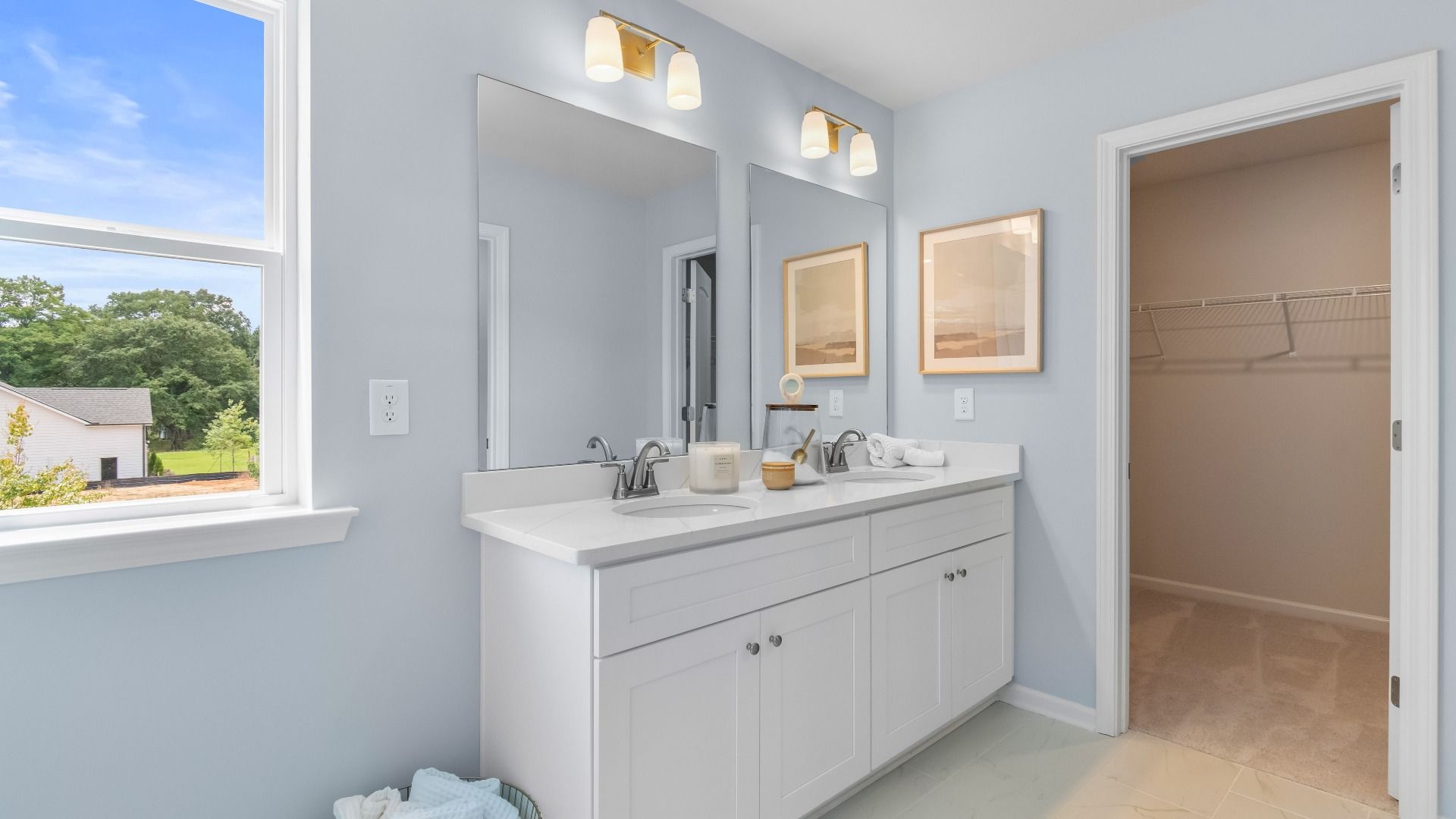 Bathroom with double vanities, quartz countertops, modern fixtures, and large mirror in new construction townhome.