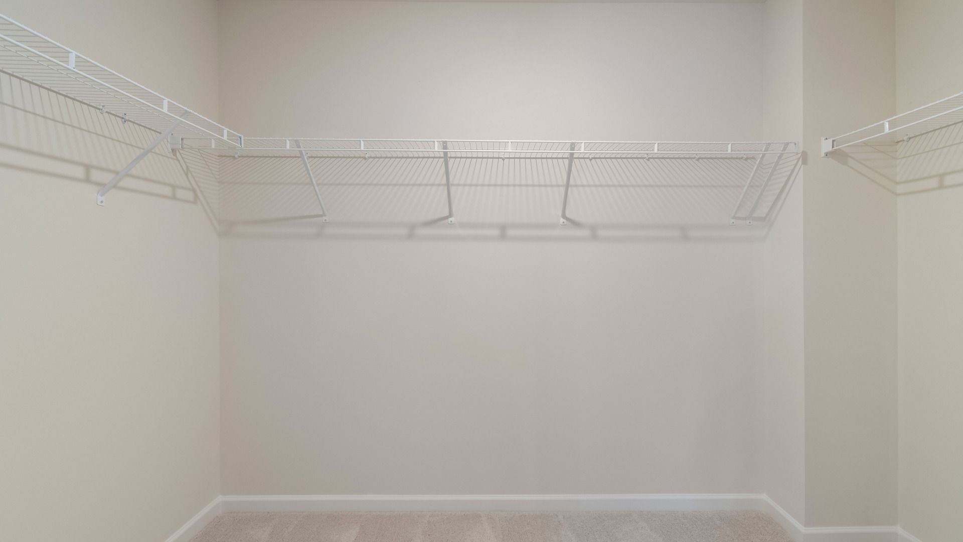 Generous walk-in closet with built-in shelves, hanging rods, and storage space in new construction townhome.