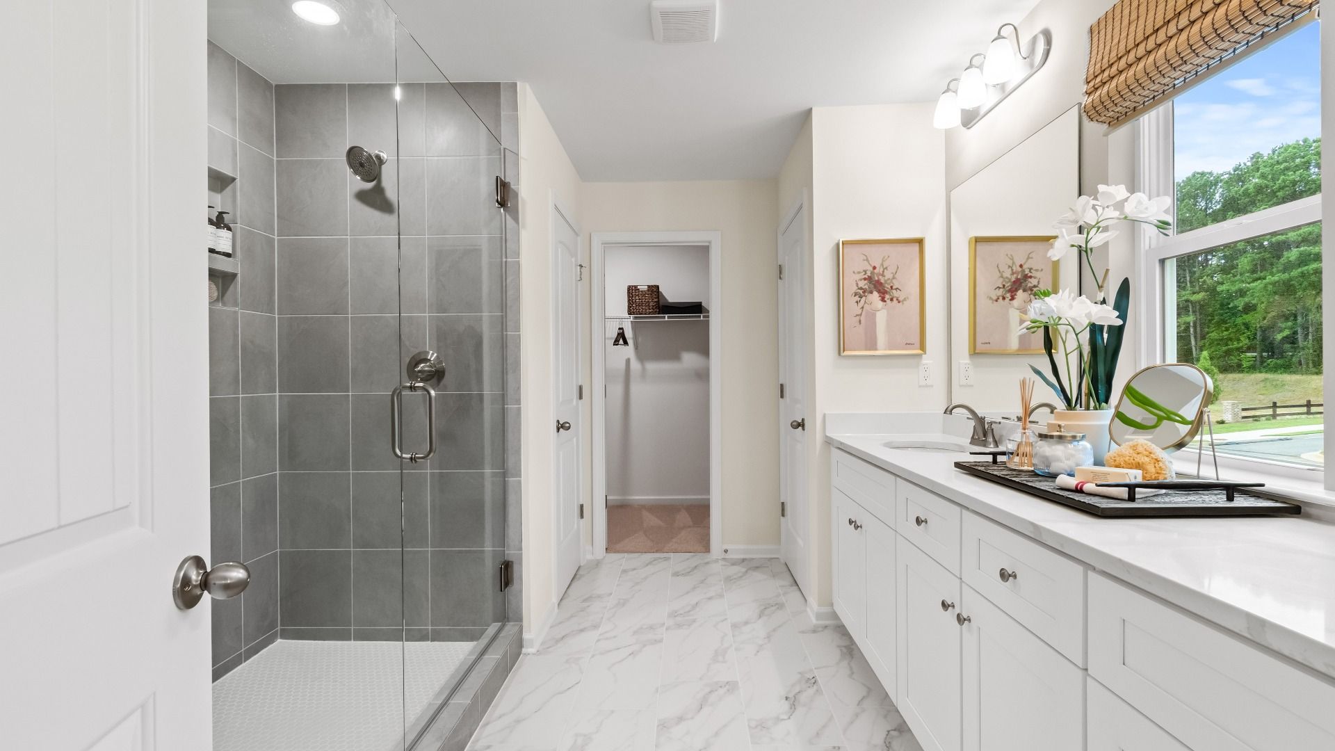 Luxury primary bath with double vanity, marble flooring, and sleek shower space in Hamilton Lakes in Lawrenceville, GA.