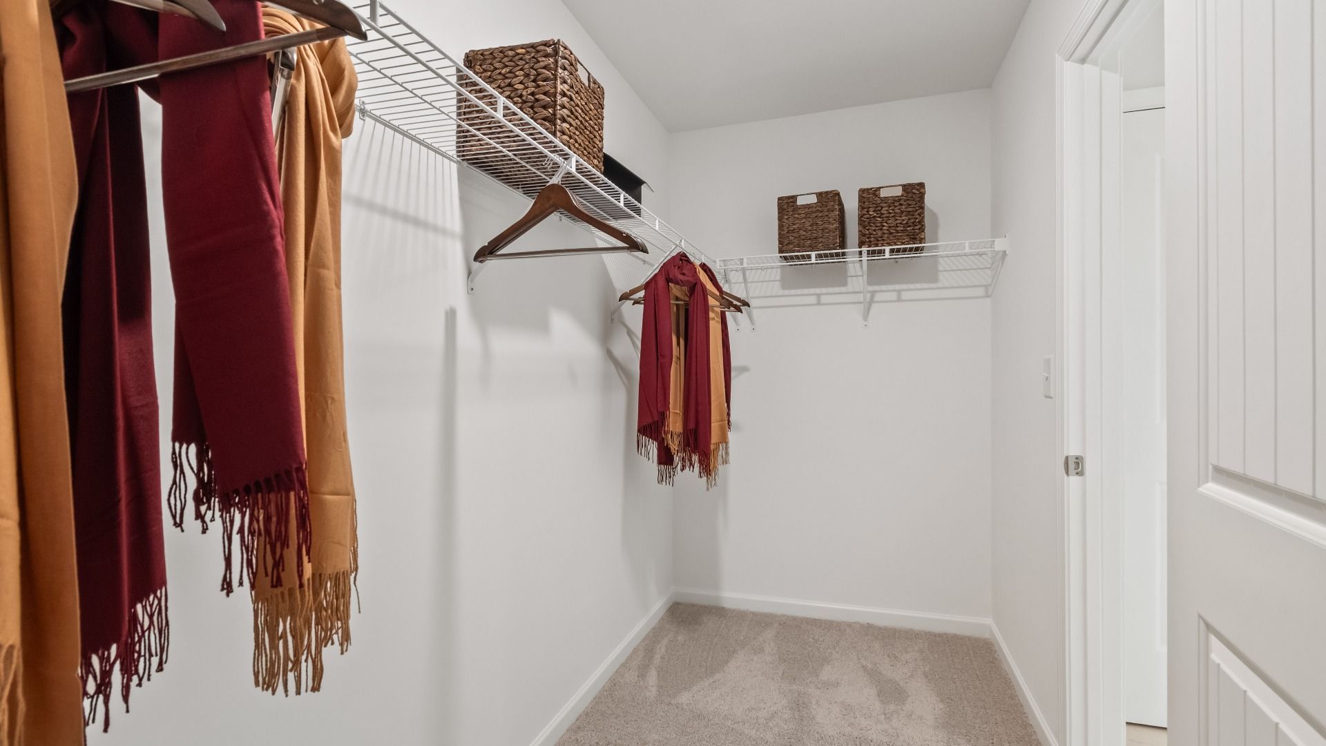 Primary closet with carpet flooring and built-in shelves for storage in the Wynwood plan at Abbotts Crossing.
