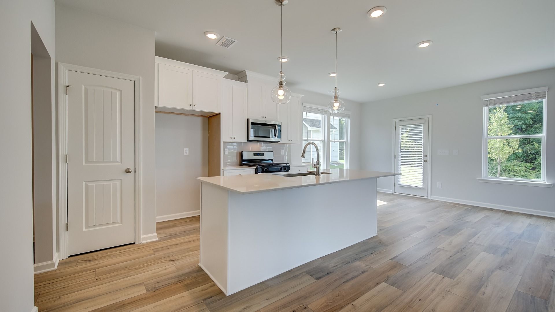Modern kitchen in new construction home with large island, quartz countertops, and pendant lighting.