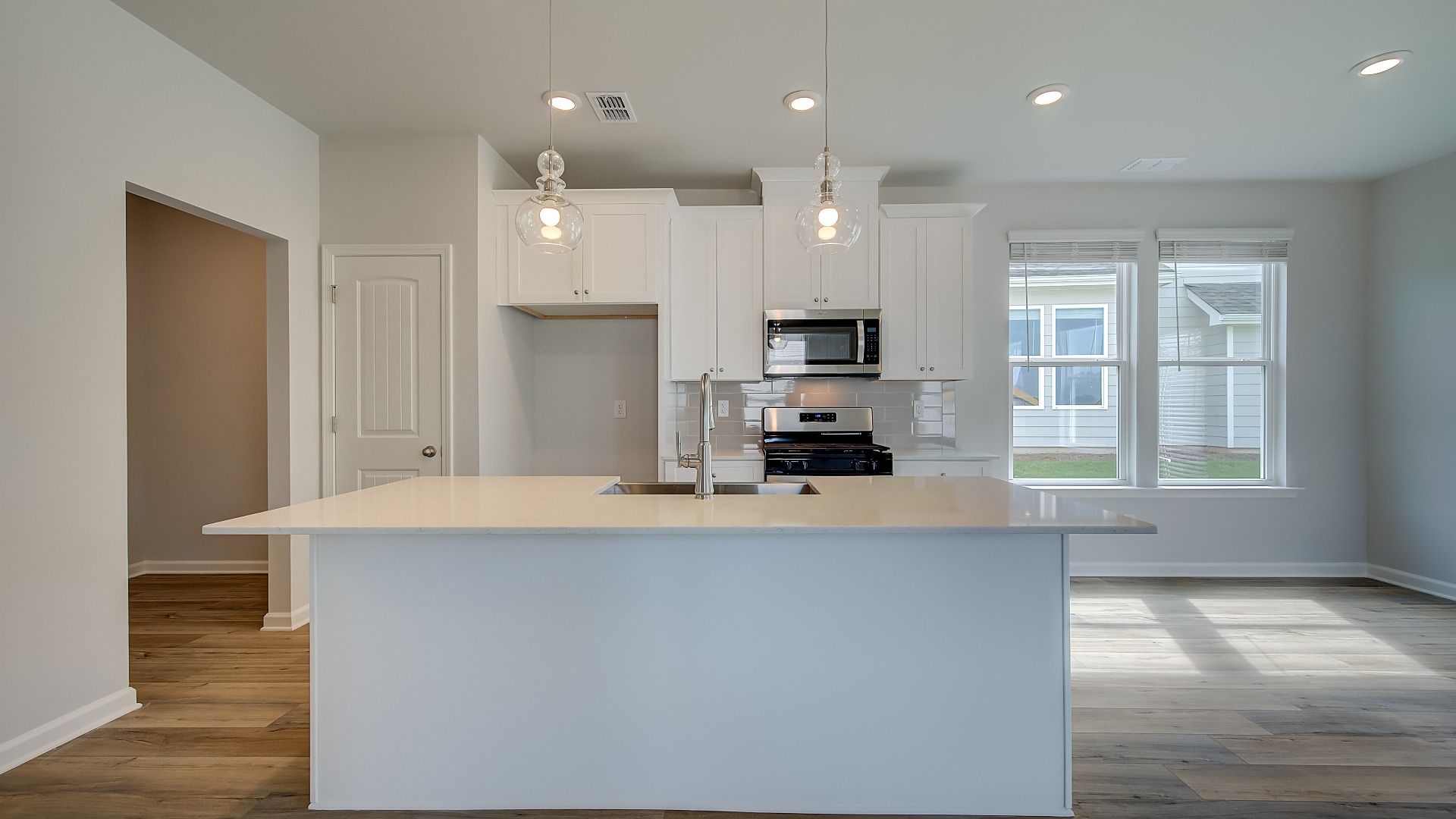 Modern kitchen in new construction home with large island, quartz countertops, and pendant lighting.