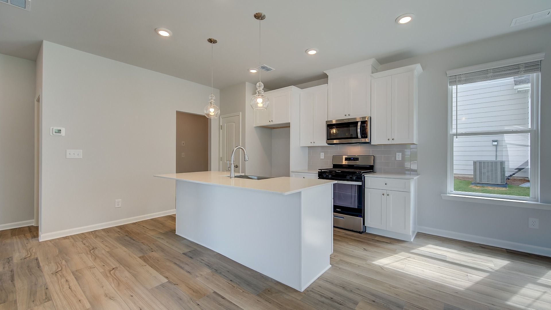Modern kitchen in new construction home with large island, quartz countertops, and pendant lighting.