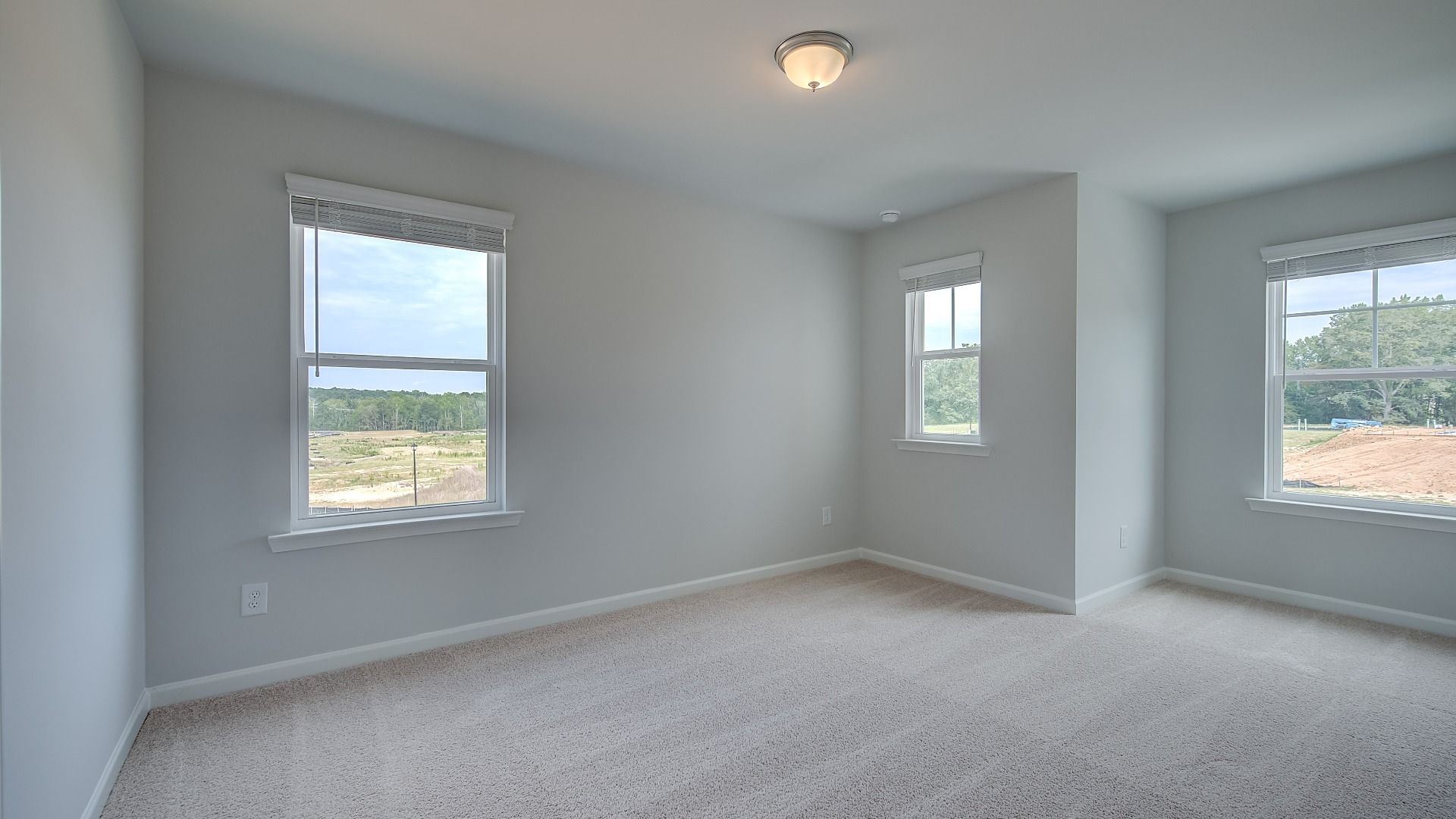Secondary bedroom in new construction townhome with large windows, natural light, and neutral finishes.
