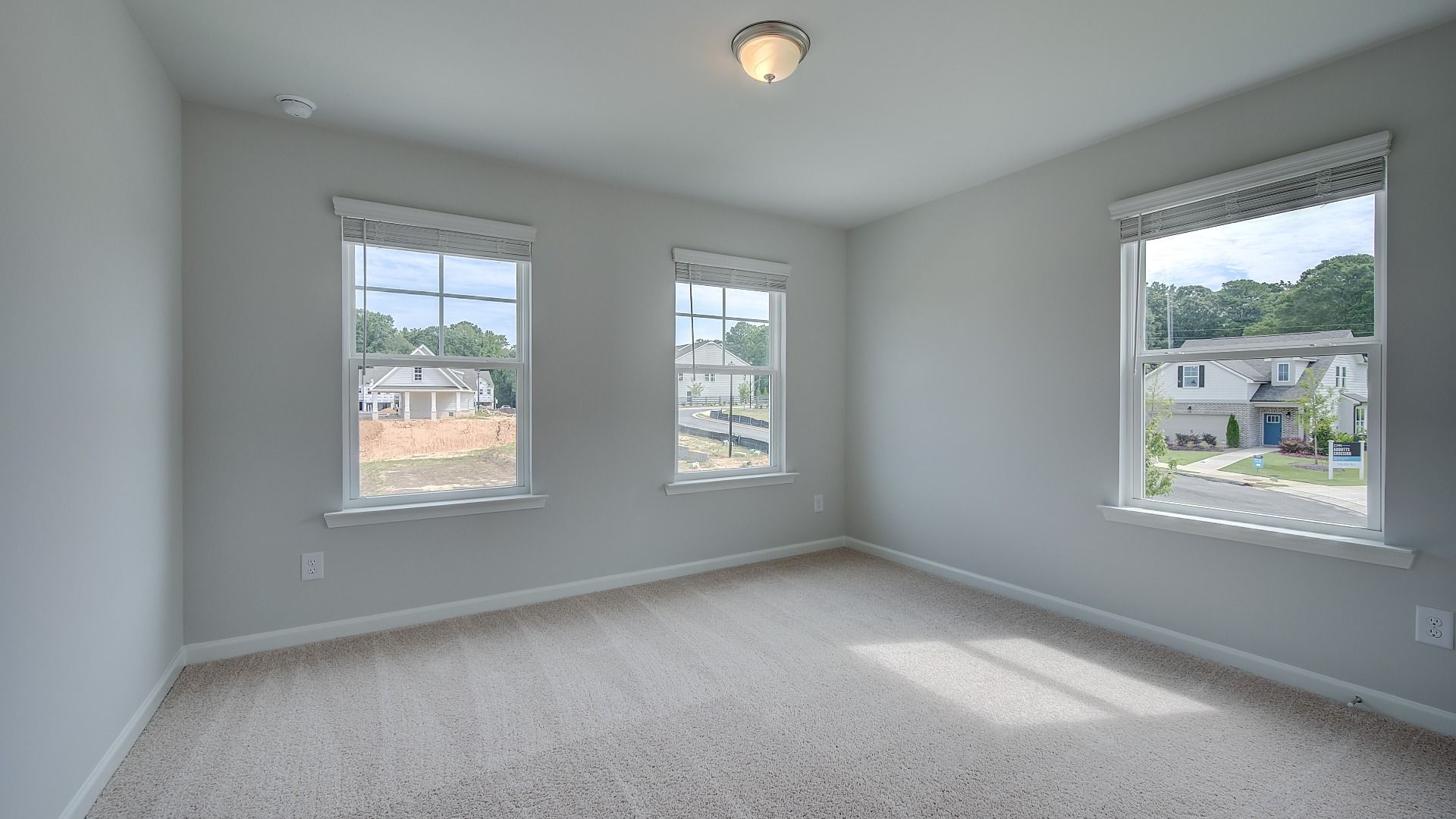 Secondary bedroom in new construction townhome with large windows, natural light, and neutral finishes.