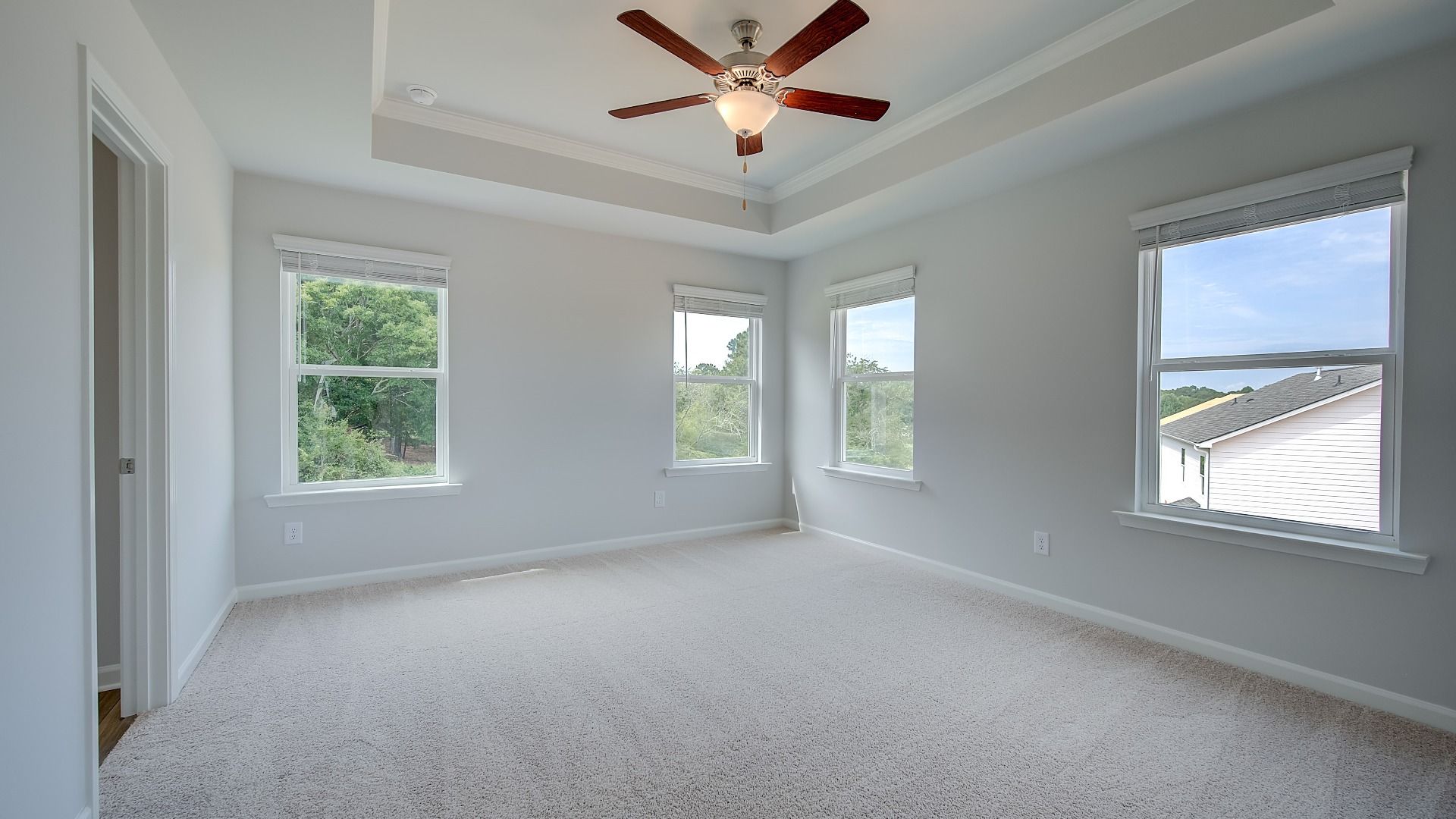 Inviting primary suite with ceiling fan, ample daylight, and modern finishes in new construction residence.