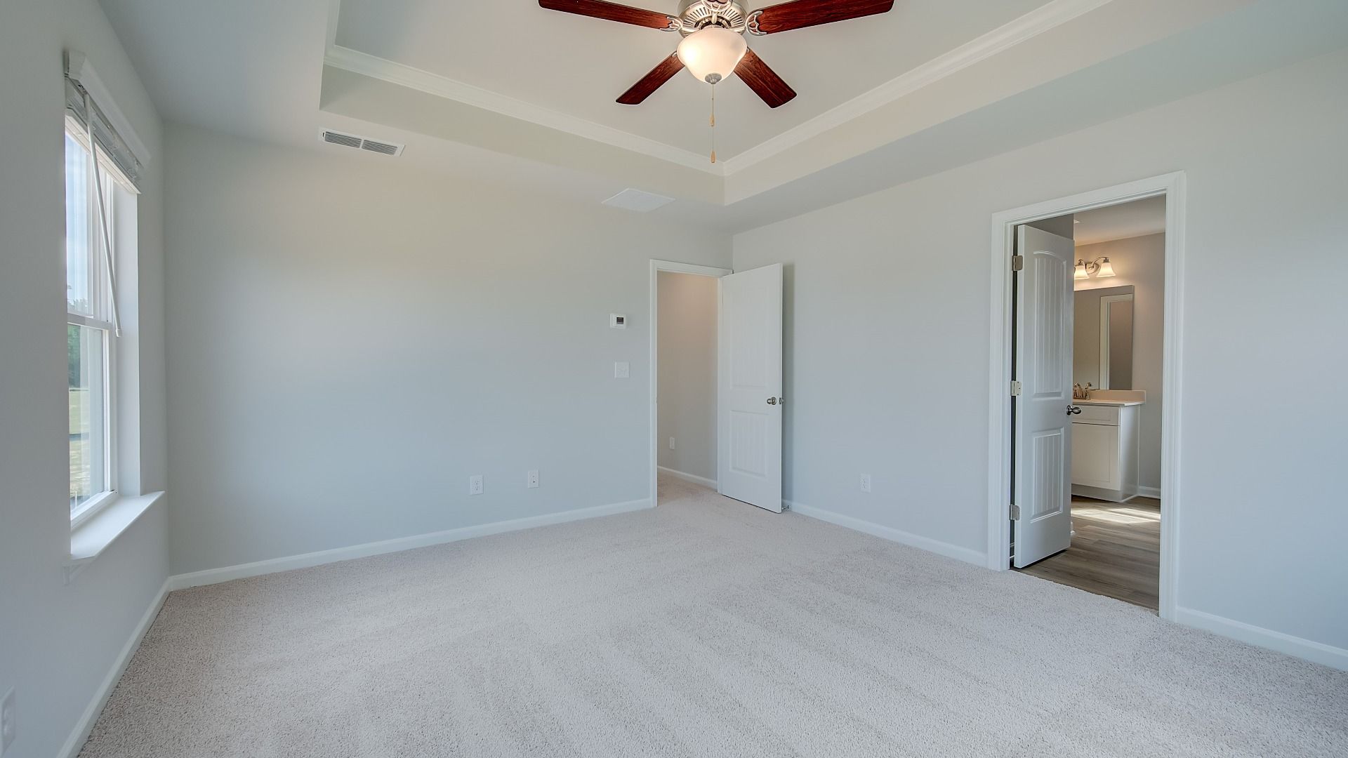Inviting primary suite with ceiling fan, ample daylight, and modern finishes in new construction residence.