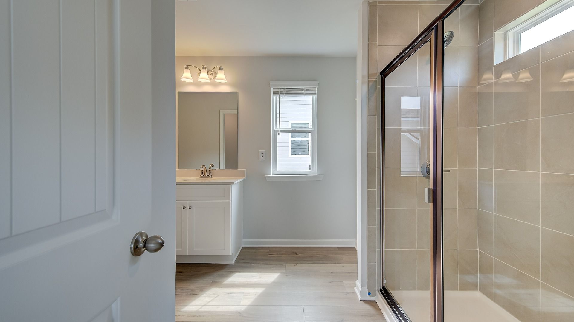 Primary bathroom with dual vanities, large walk-in shower, and modern quartz countertops in new construction home.