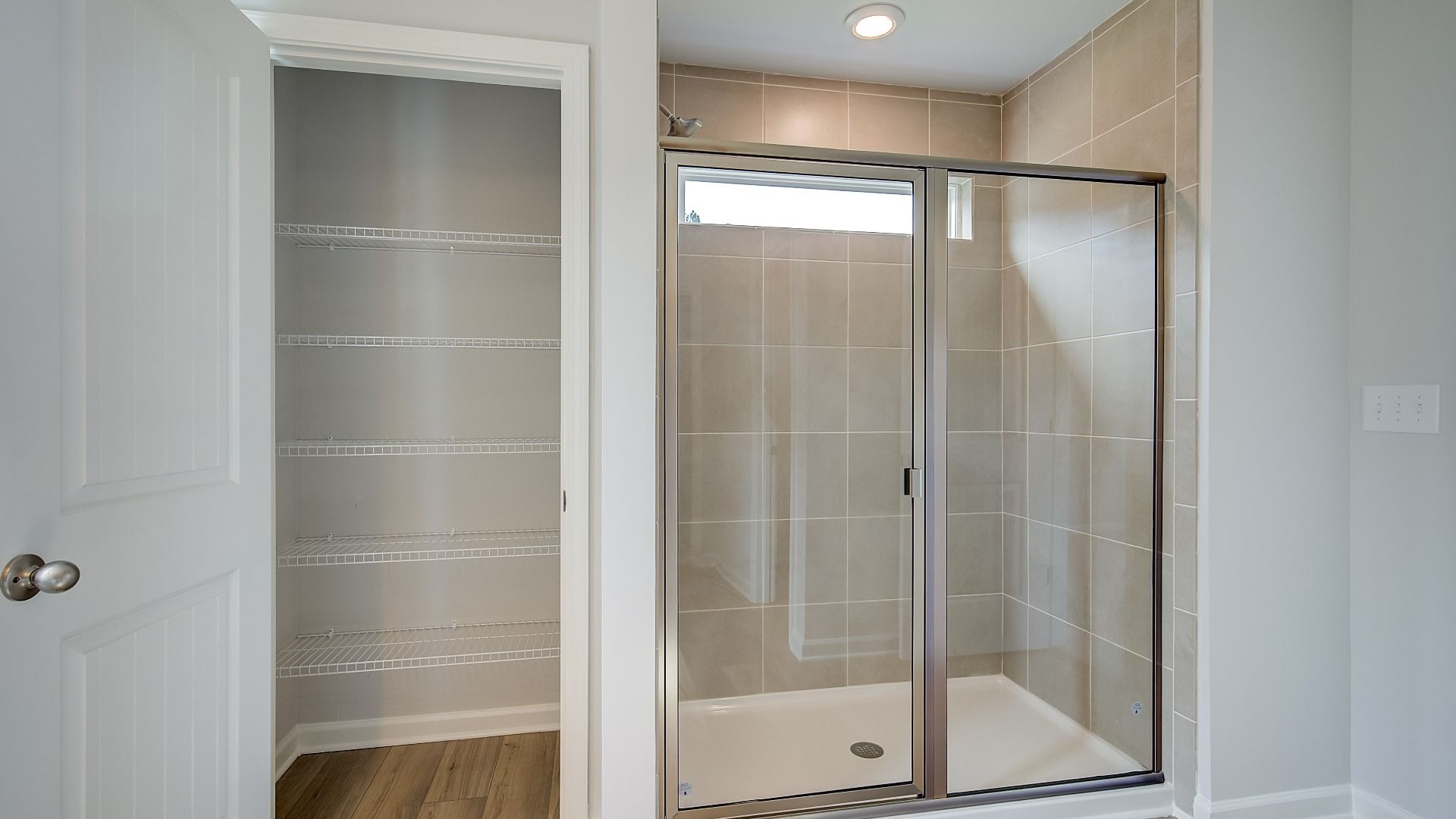 Glass-enclosed shower with tile walls and sleek modern fixtures in primary bathroom.