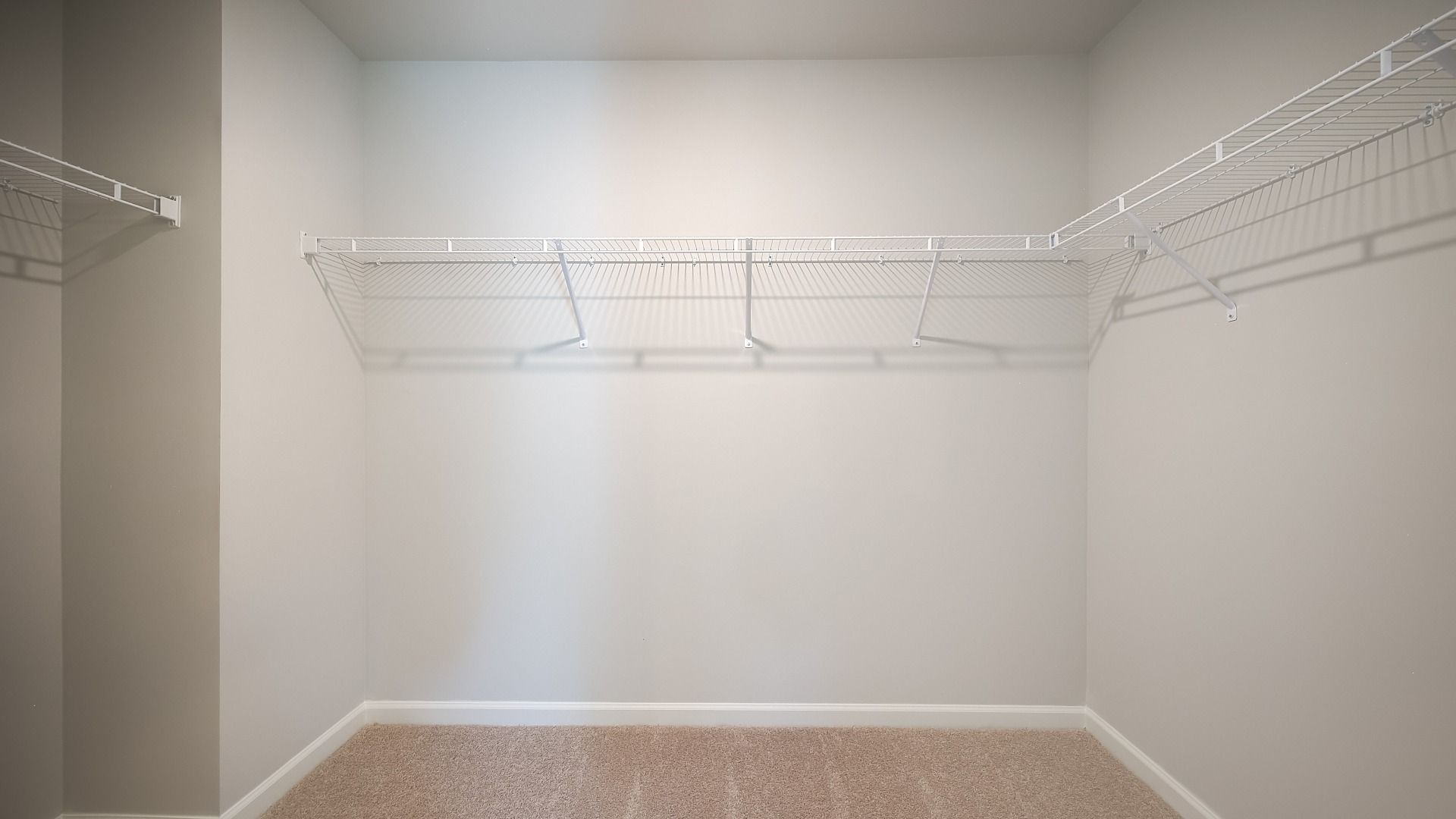 Generous walk-in closet with built-in shelves, hanging rods, and storage space in new construction home.