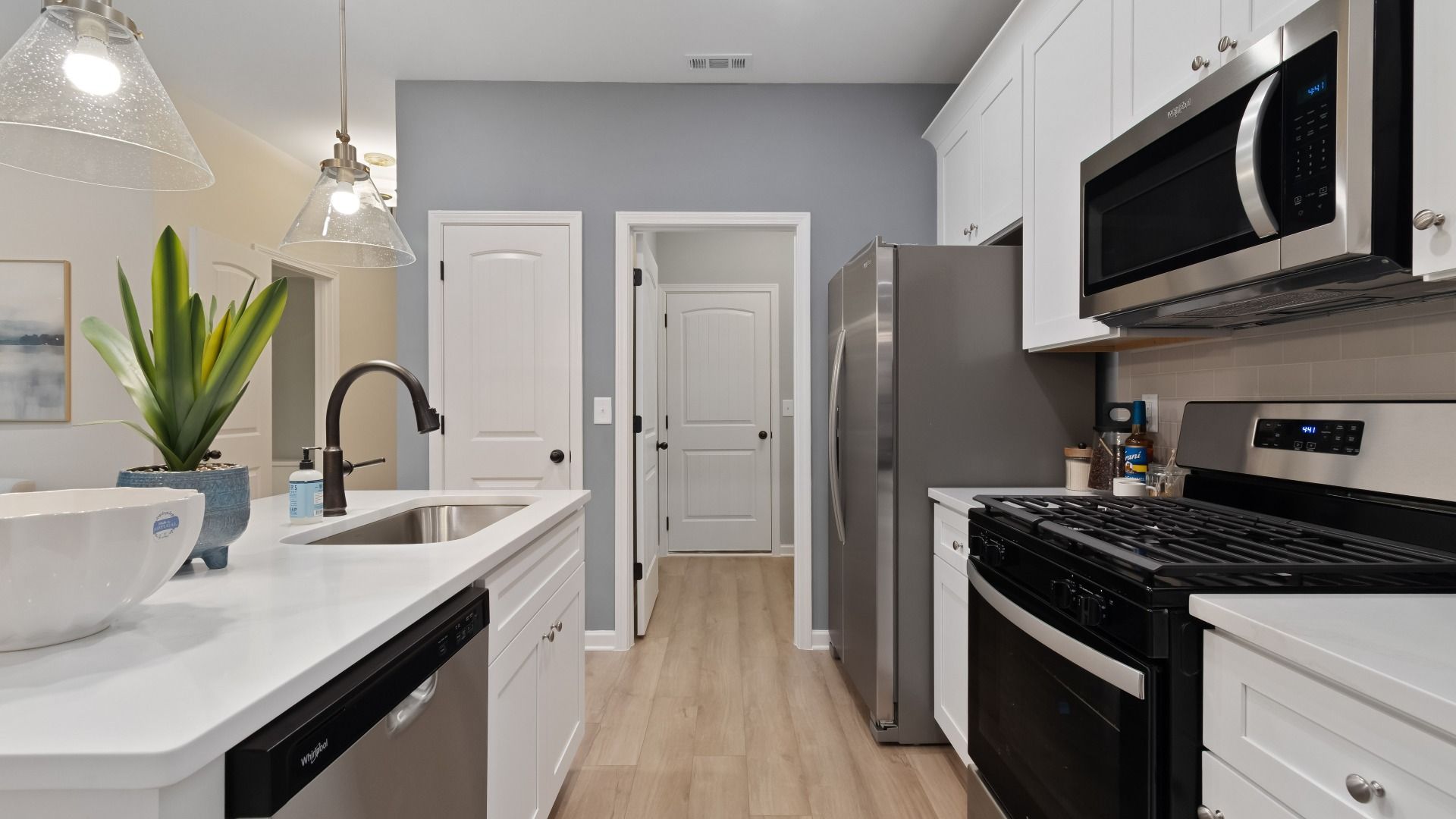 Bright open kitchen featuring center island, white cabinets, quartz counters, and stainless steel range and microwave.