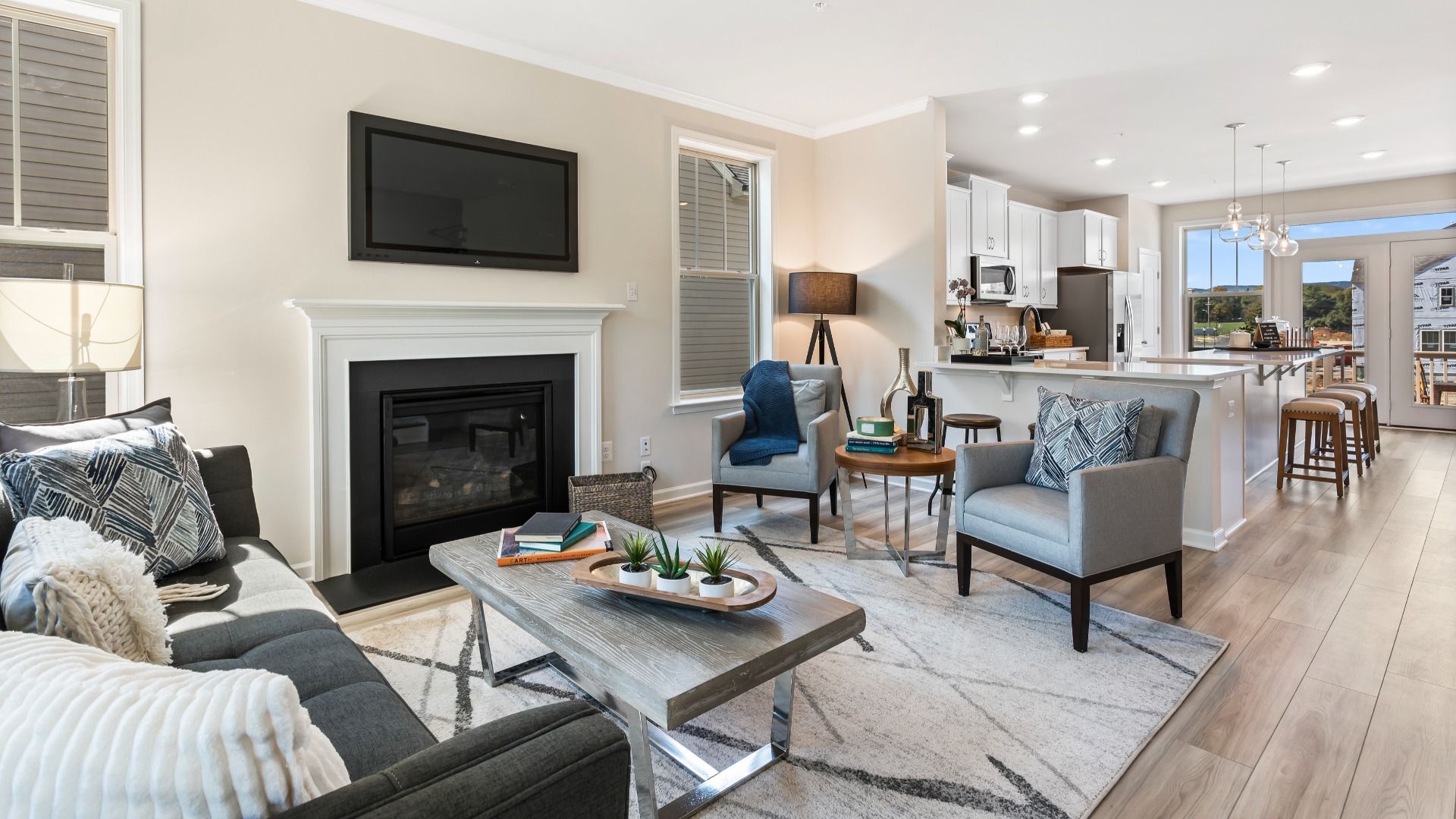 Living room with fireplace and adjacent kitchen at a DRB Homes Upton II Model at the Canterbury Station Community.