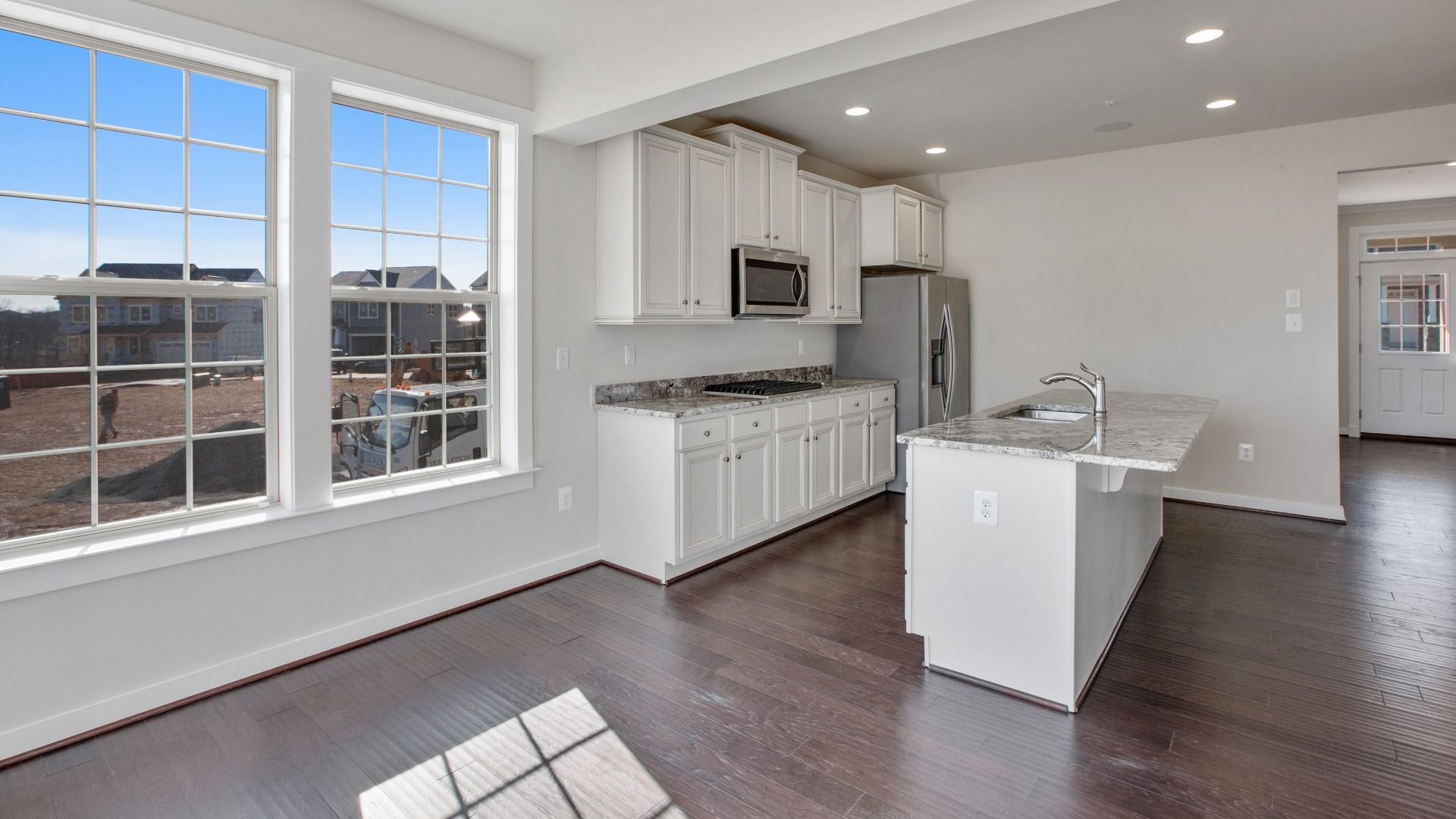 Kitchen with white cabinets, light counters, large, in sink island and large double window in breakfast area