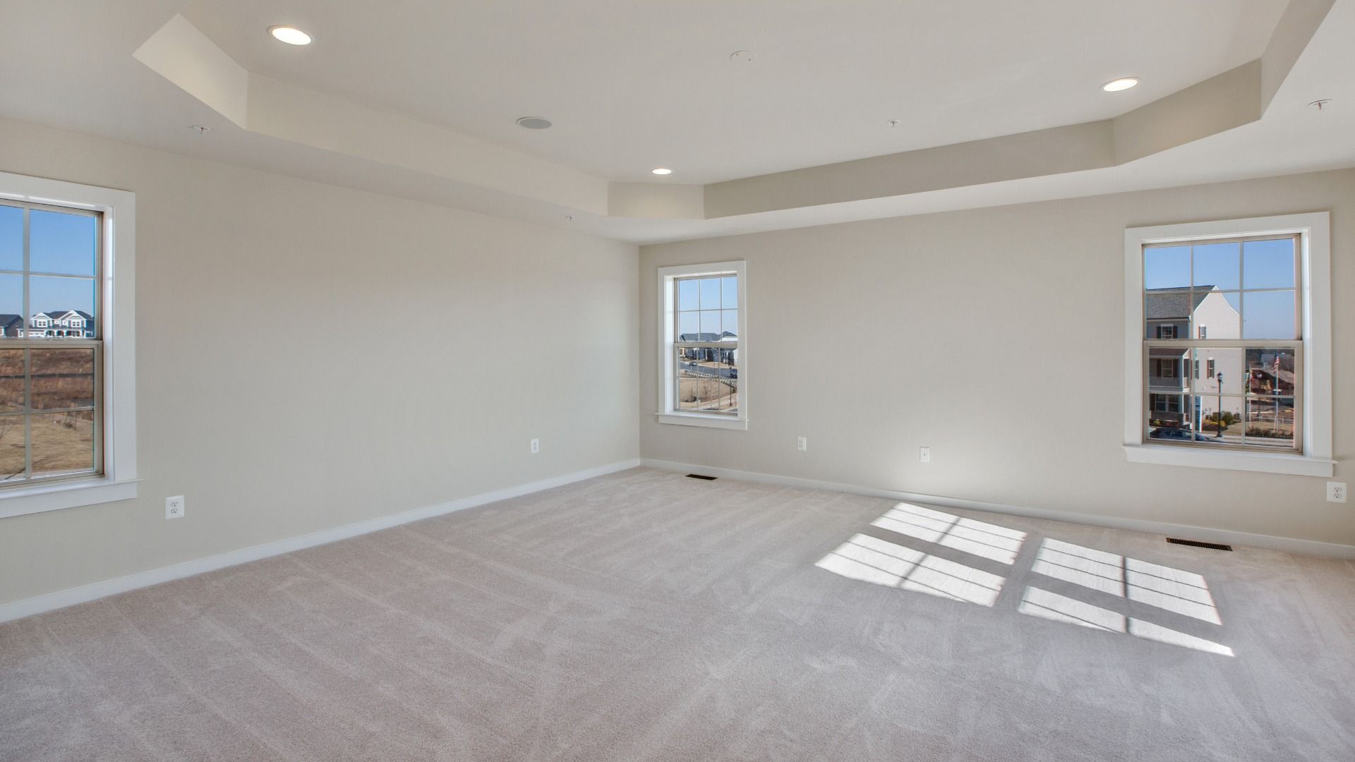 Spacious owner's suite with light colored wall to wall carpet, tray ceiling, recessed lights & 3 large windows on 2 walls.