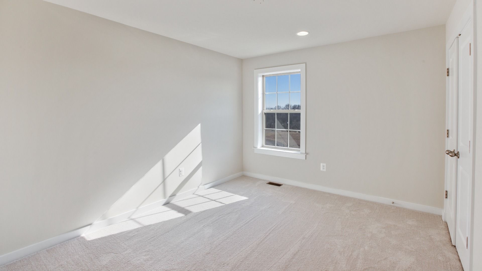 Secondary bedroom with light colored wall to wall carpet, single window and recessed lights