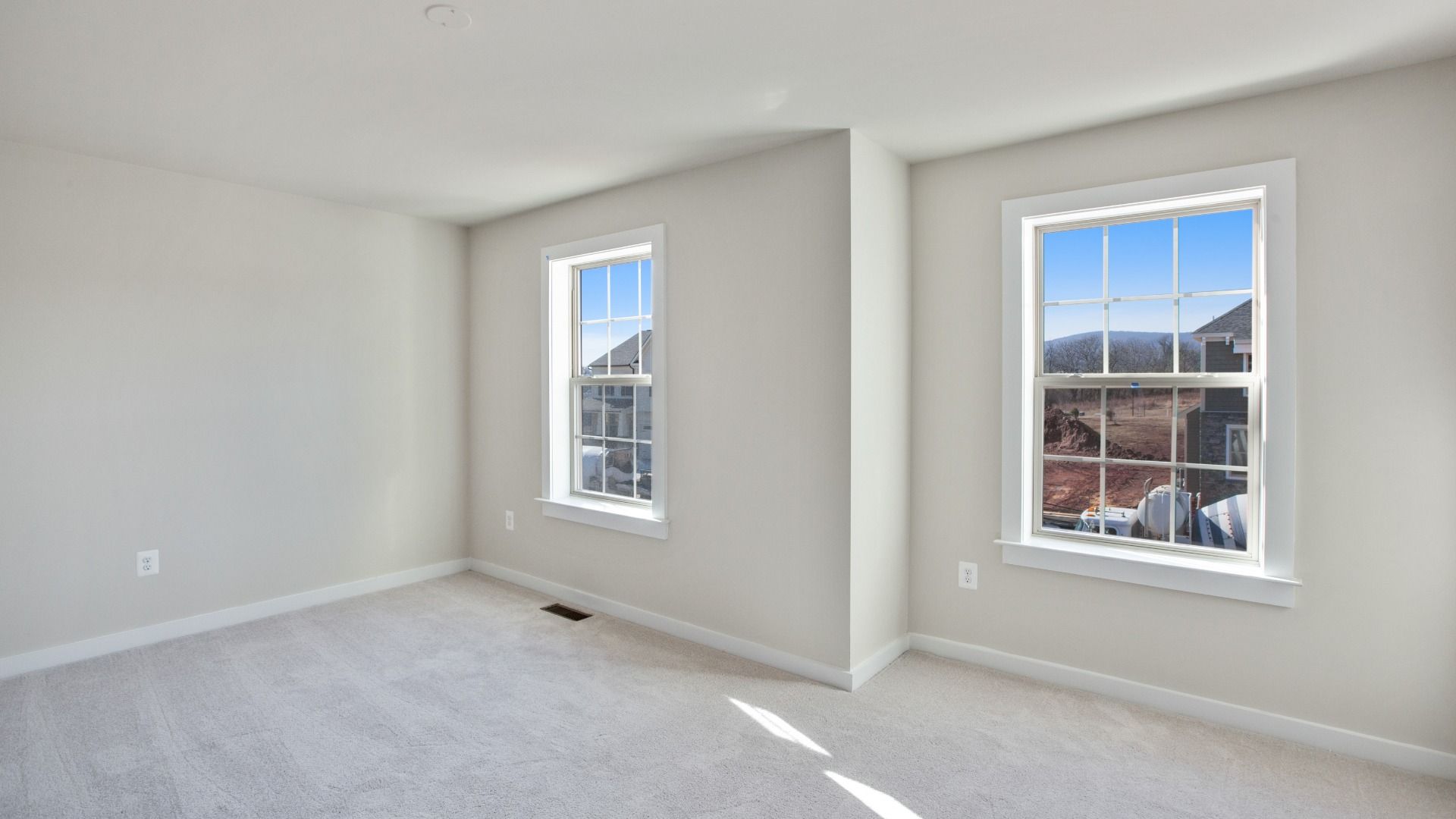 Spacious secondary bedroom with light colored wall to wall carpet and 2 large windows along single wall