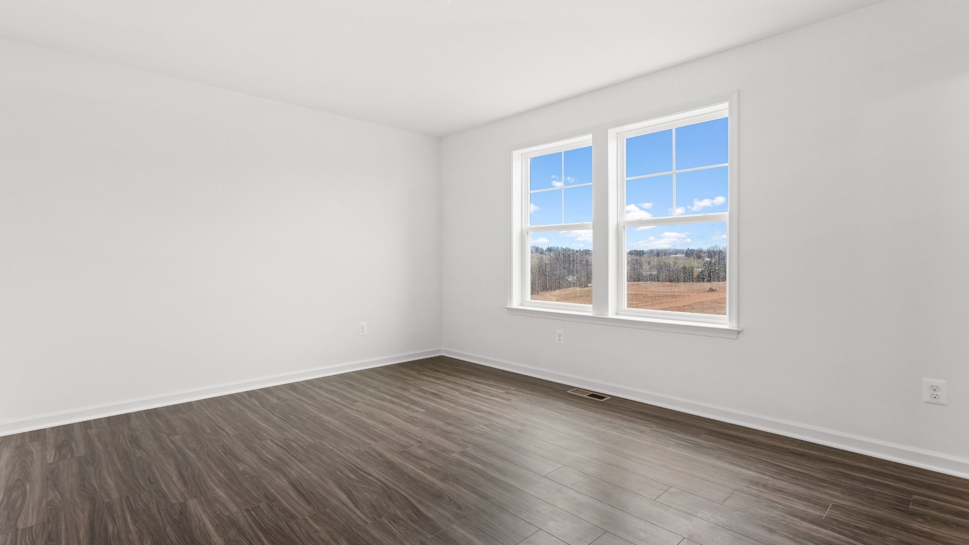 Secondary bedroom with double window and wood floors in a DRB Homes Bridgeport home plan at Huntfield in Charles Town, WV