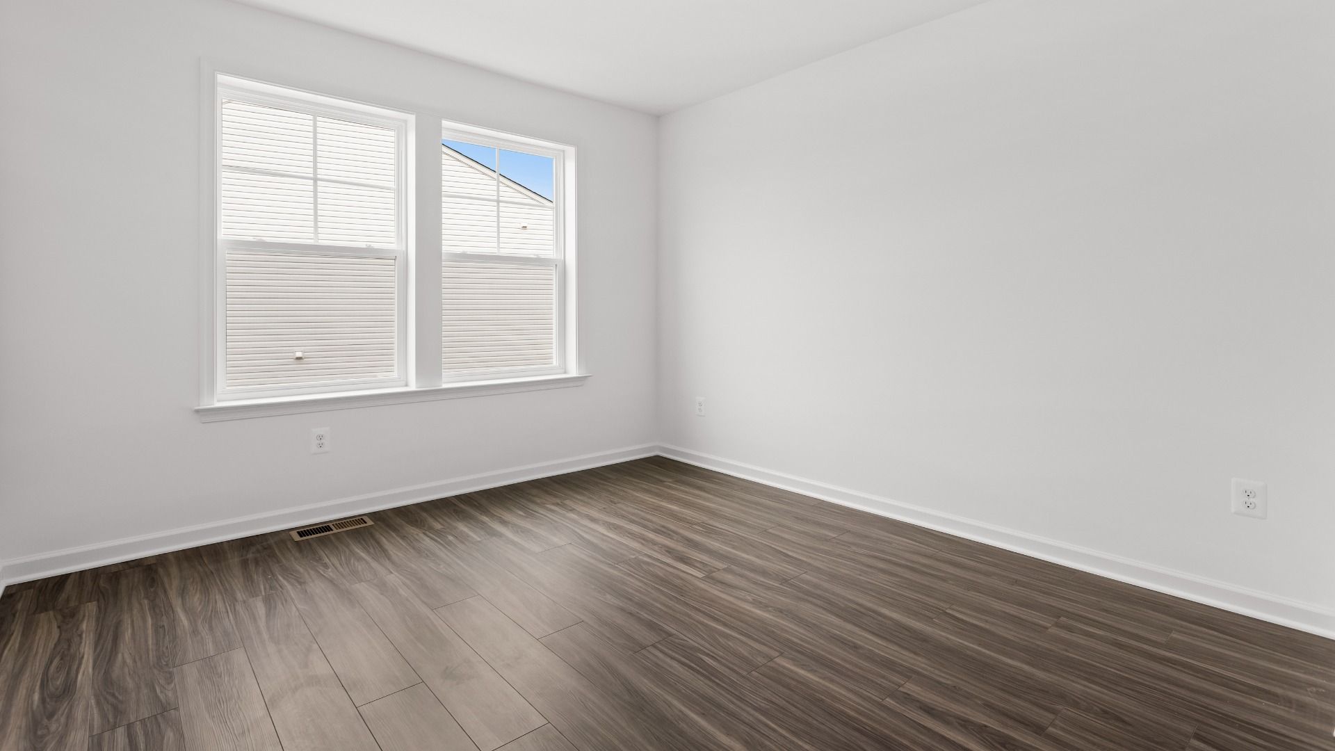 Secondary bedroom with wood floors & double window in a DRB Homes Bridgeport home plan at Huntfield in Charles Town, WV