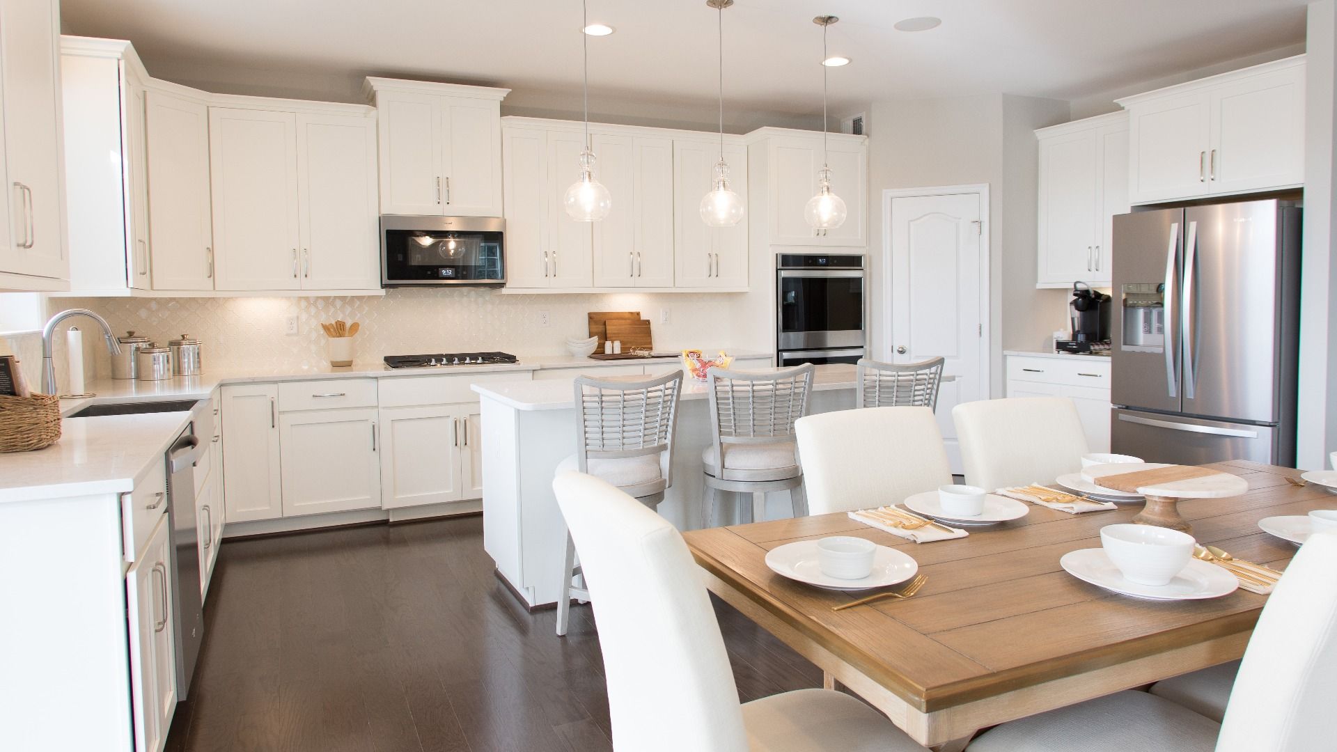 Island kitchen with white cabinets and stainless appliances in a DRB Homes Cypress II home plan at Huntfield.