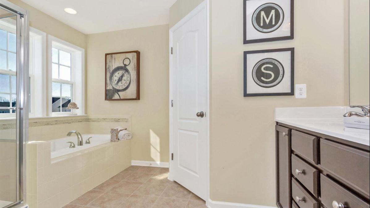 Bathroom in the Newbury II Single Family Home by DRB Homes with a Spacious Layout with Modern Fixtures and Glass Door Shower.