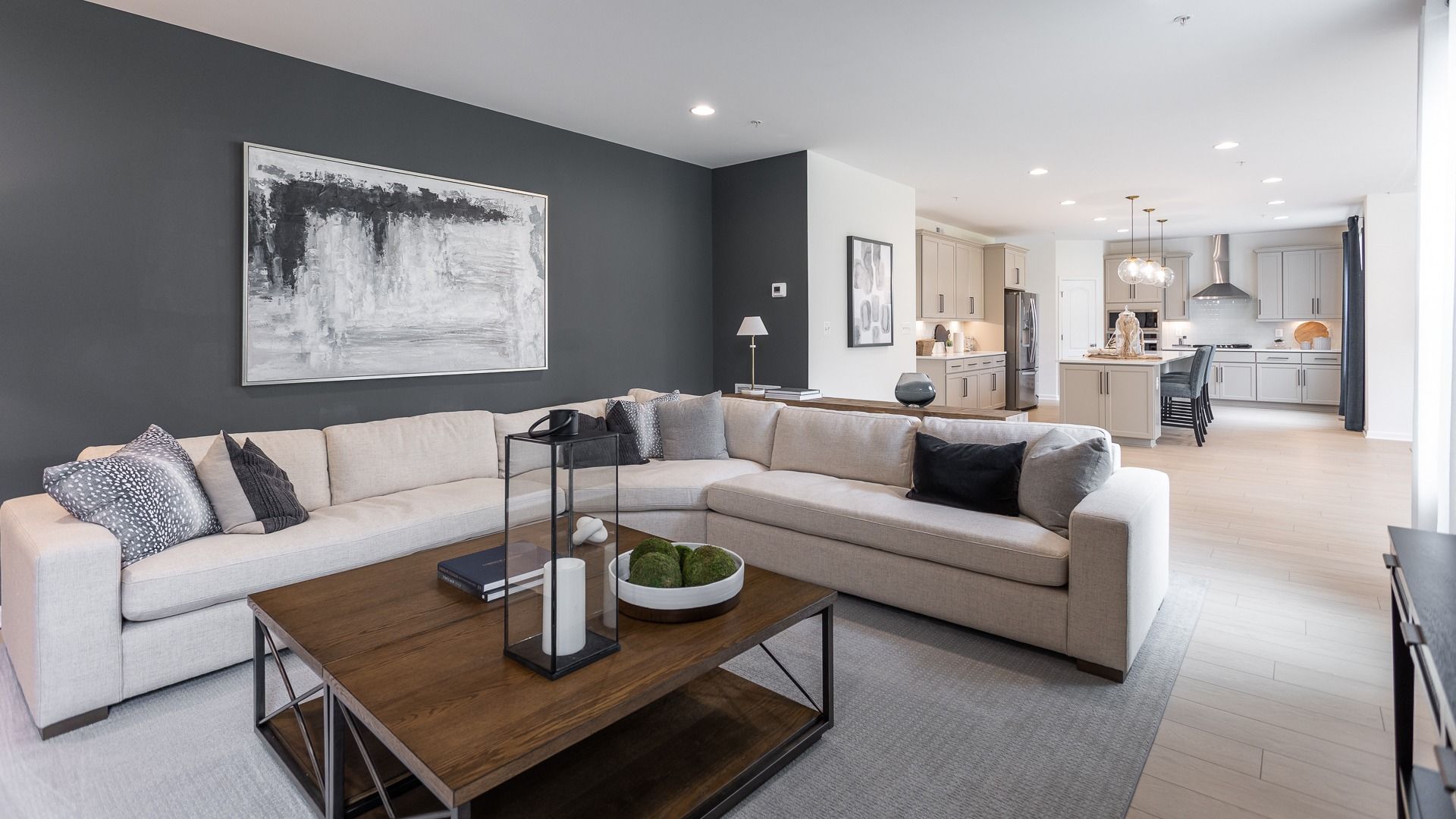 Open and inviting Oakdale II living room seamlessly flows into a modern kitchen backdrop.