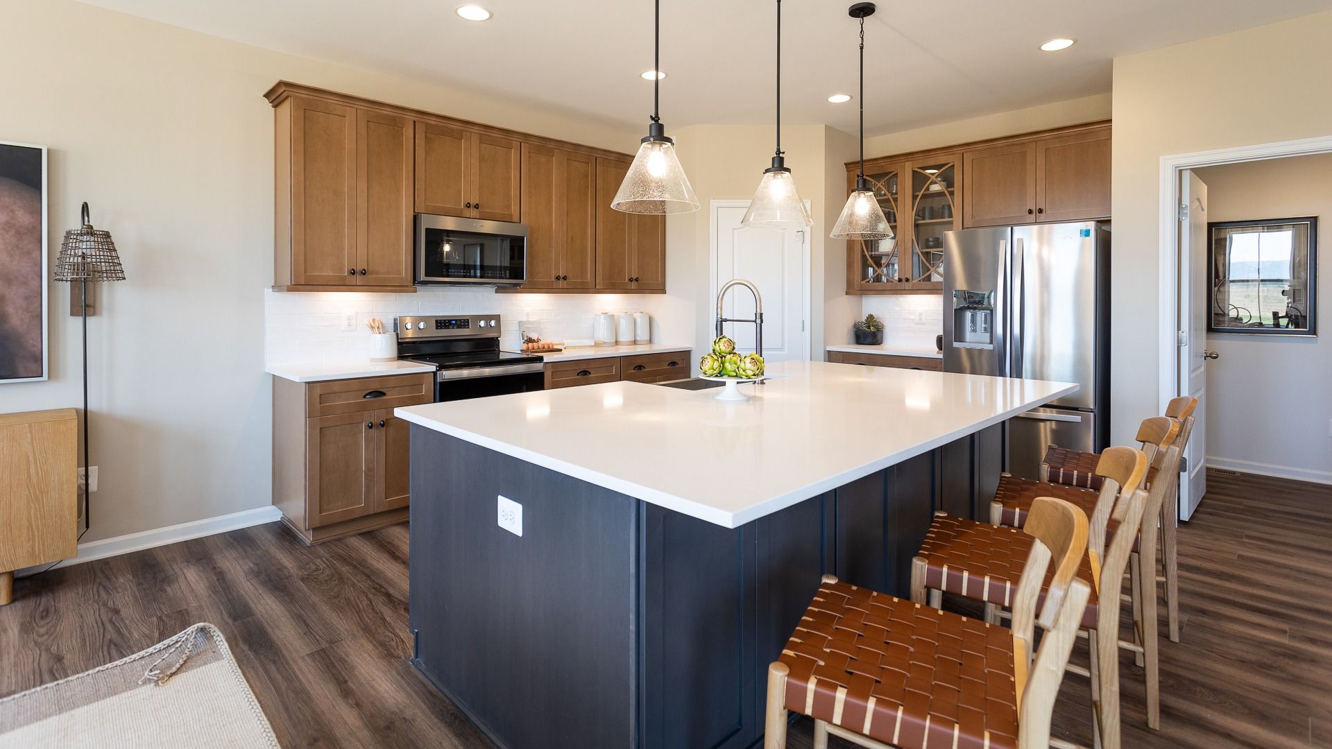 Island kitchen with 2-tone cabinets, white stone counters in a DRB Homes Castlerock II home plan at Huntfield.