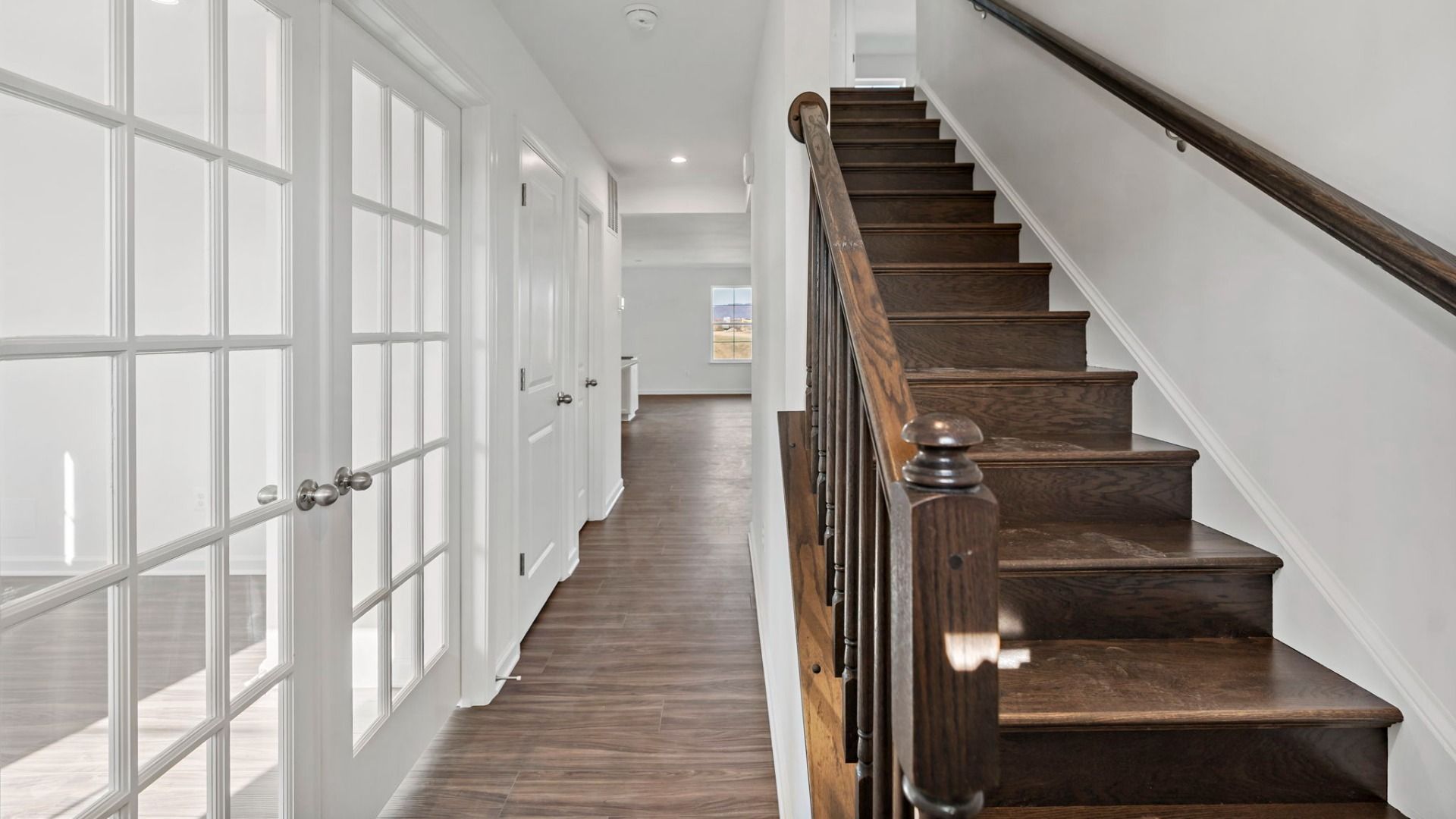 The charming grand entrance in the Carnegie II, featuring a stunning staircase and French doors.