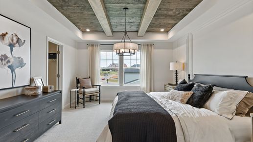 Bedroom with a rustic ceiling, large window, and furnishings in the York II Garage floor plan at The Gallery.