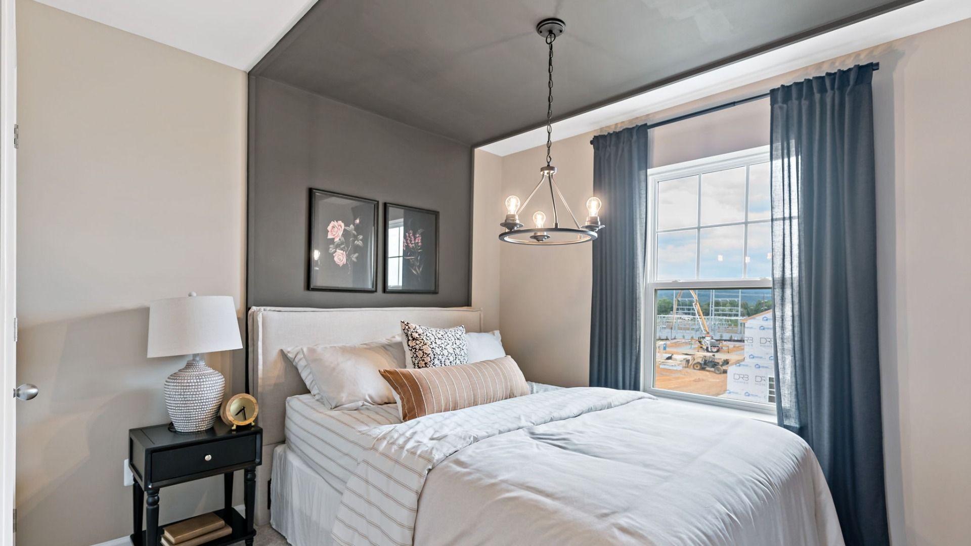 Bedroom with a chandelier, comfortable bed, and floral artwork with a view of construction from the York II Garage.
