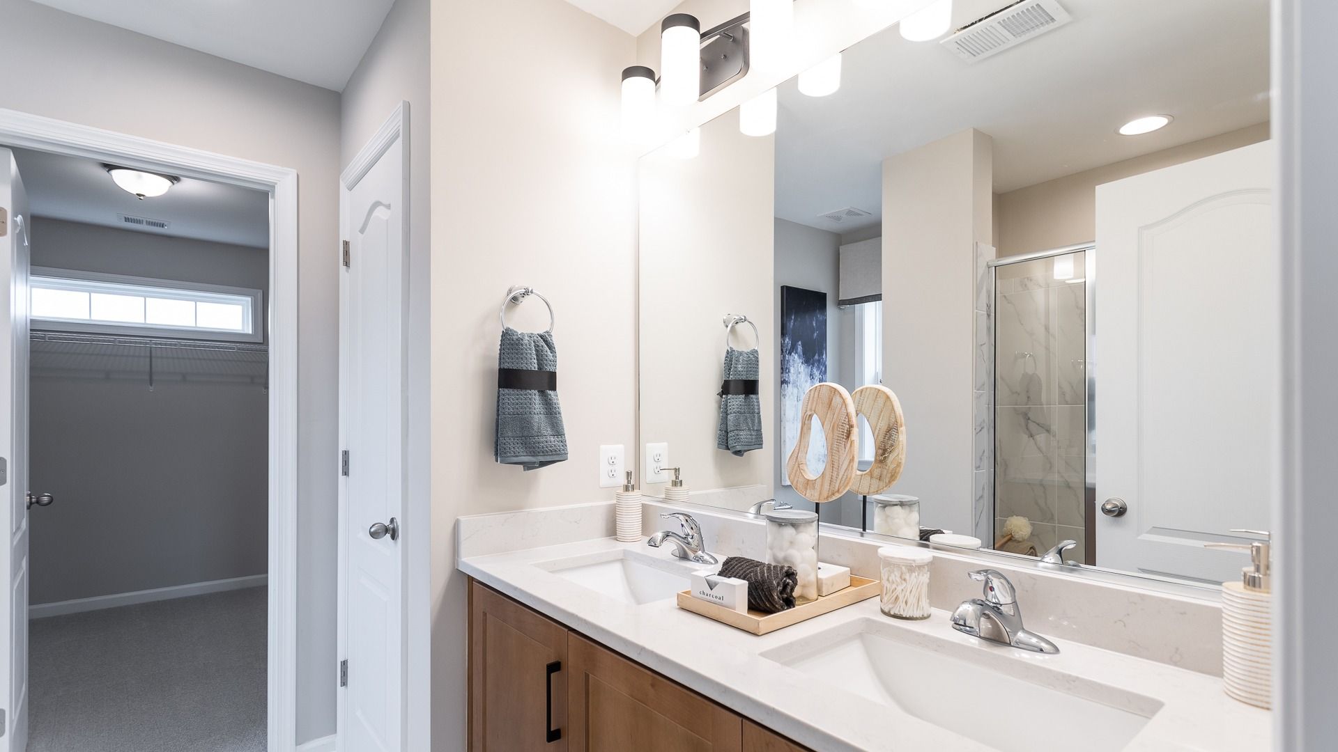 The sleek primary bath in the Carnegie II includes a dual vanity, glass shower, and closet.