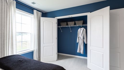 Spacious closet in the Carnegie II with double doors, and built-in shelving for organized storage.