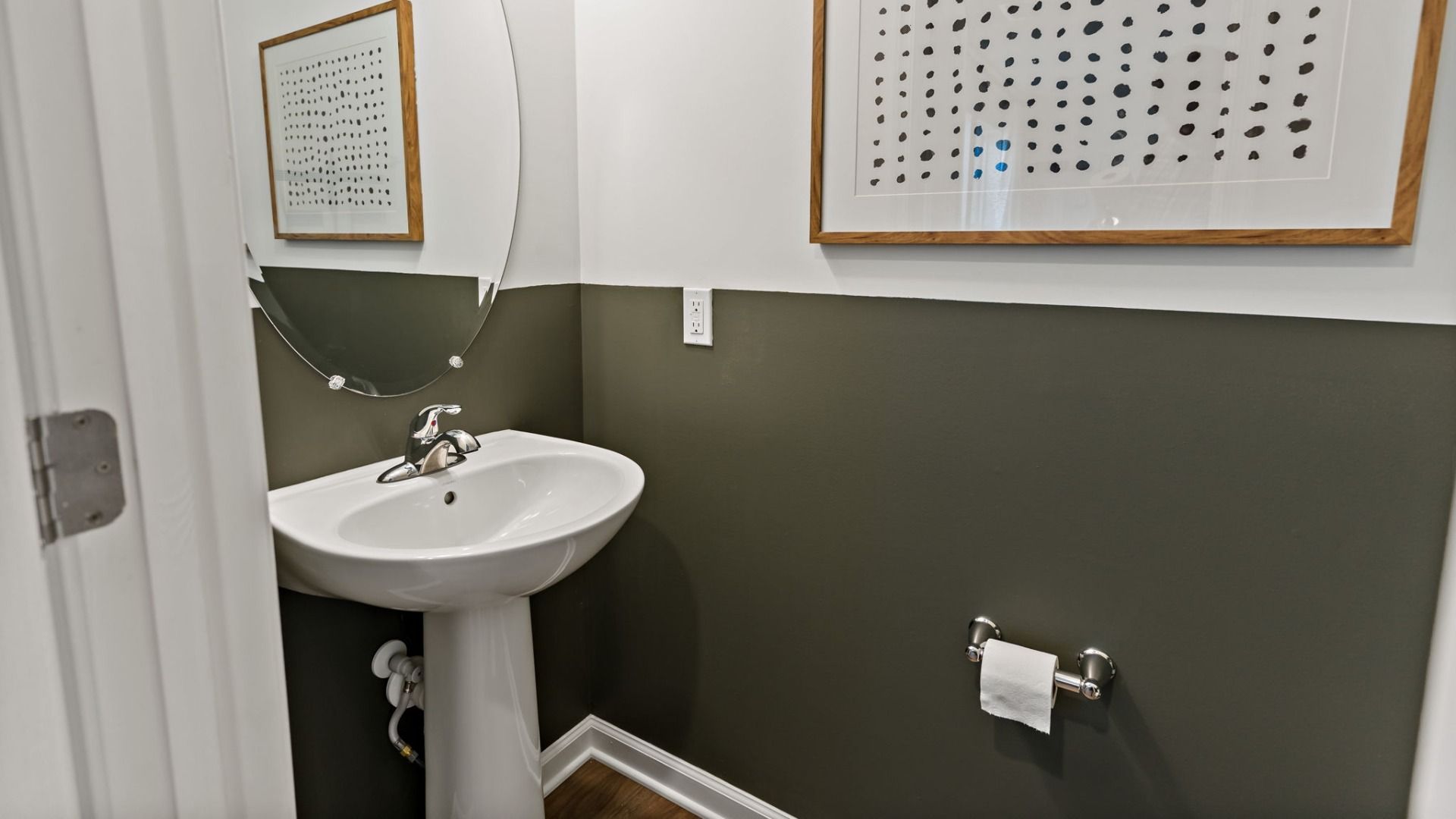 Discover the first-floor powder room featuring a sleek pedestal sink and modern finishes.