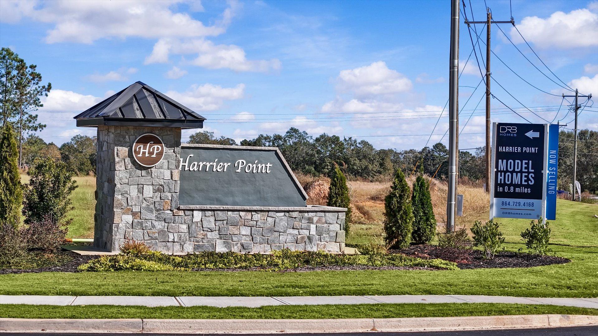 Harrier Point community entrance featuring a stone monument sign and landscaped grounds