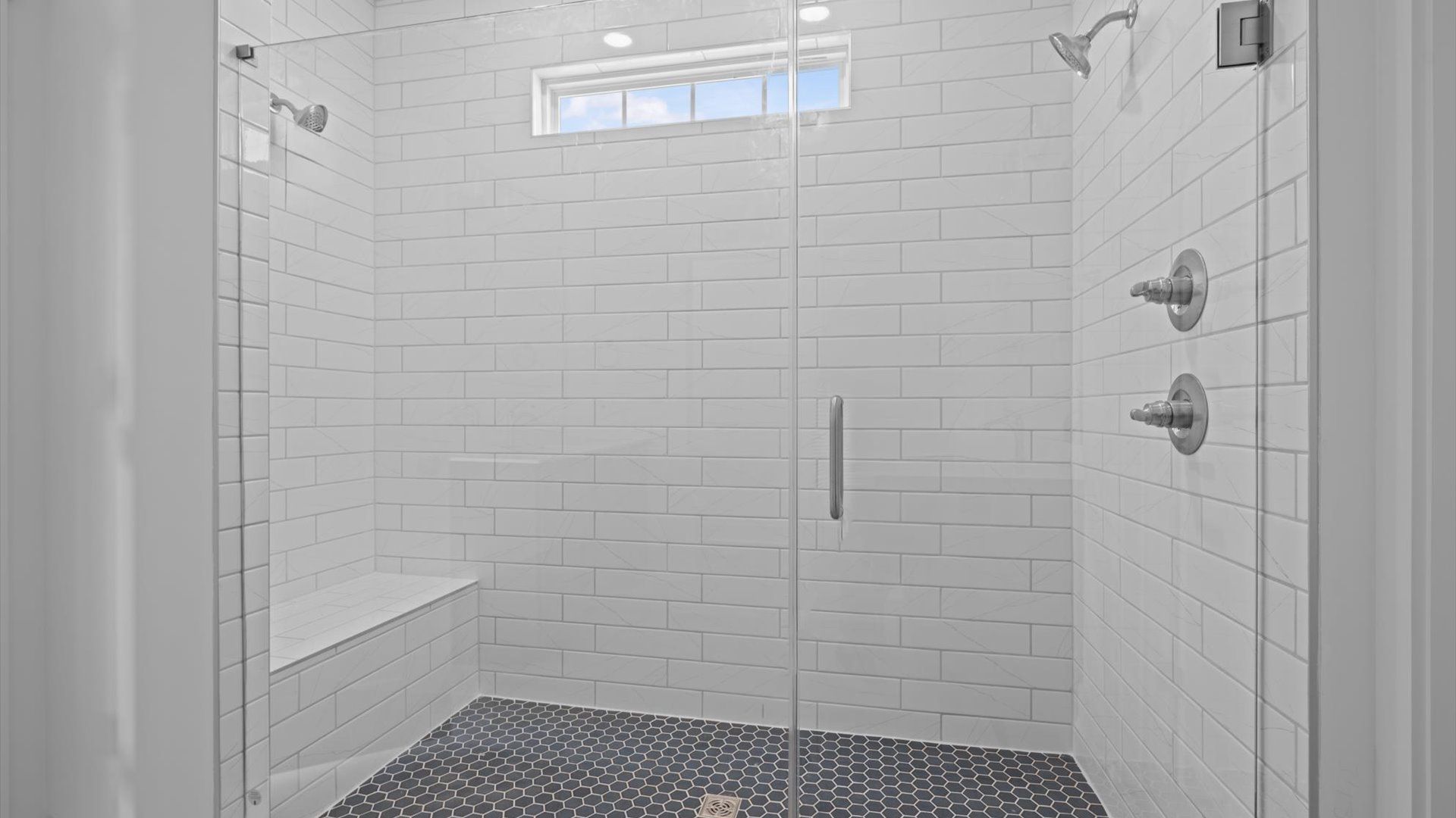 Notable primary bath featuring two vanities, tiled walk-in shower, and tasteful design touches throughout