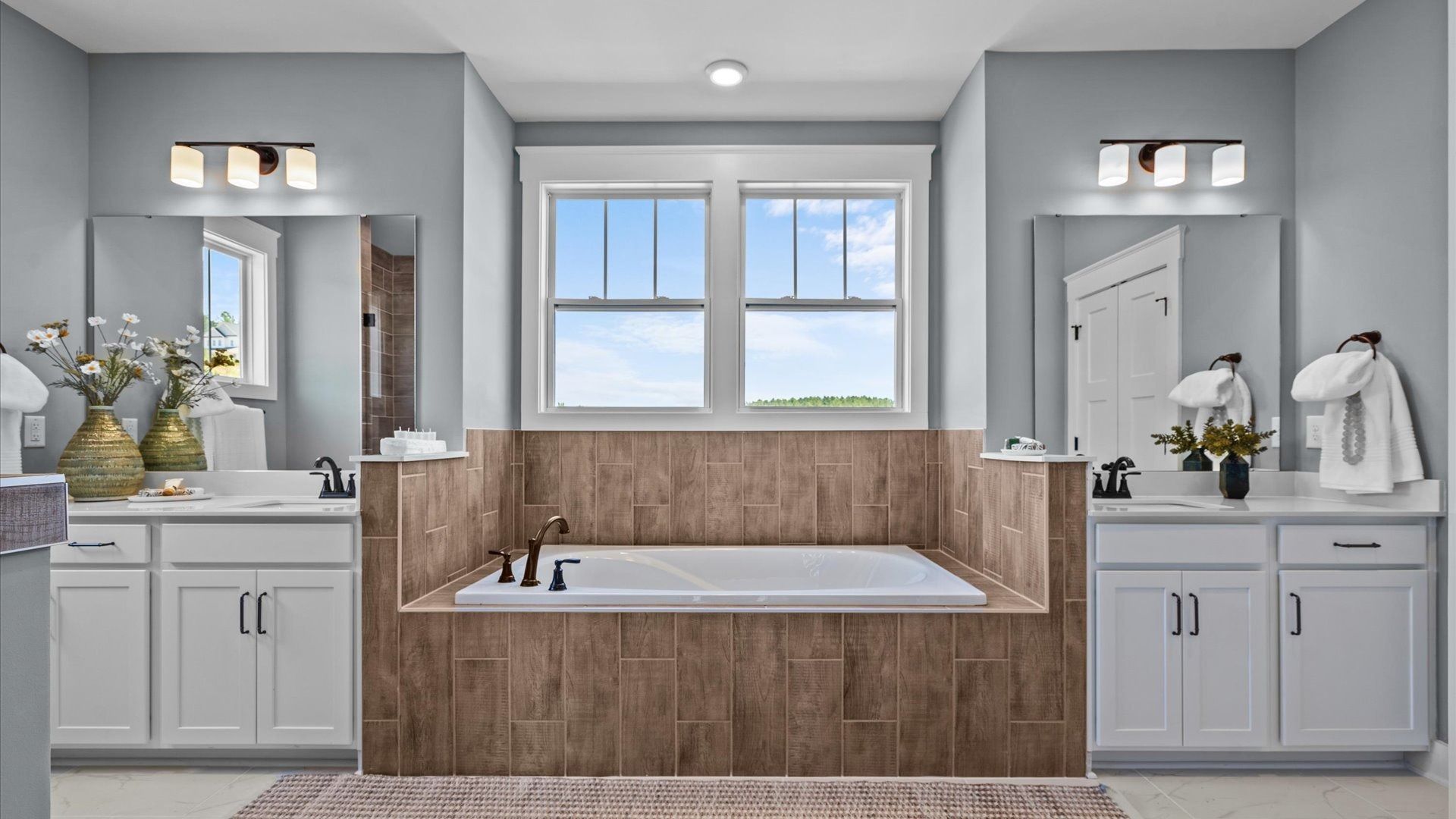 Highly functional and elegant en-suite with separate vanities, tiled walk-in shower, and soaking tub