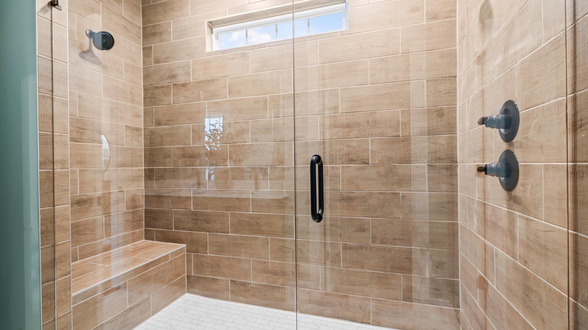 Designer en-suite featuring a frameless glass shower and elegant finishes