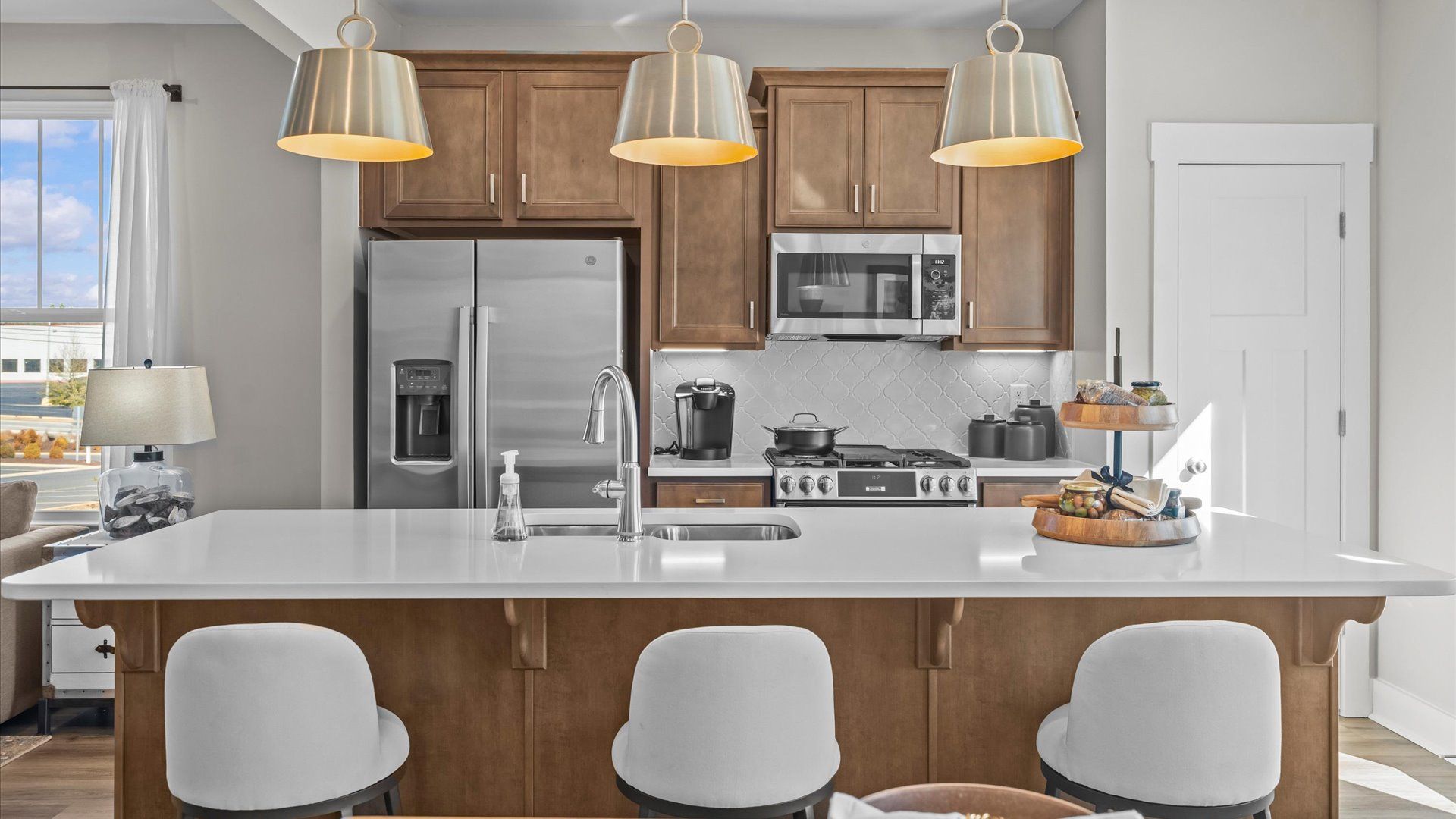 Large kitchen island with granite countertops and pendant lighting in two story townhome at Saluda Crossing by DRB Homes