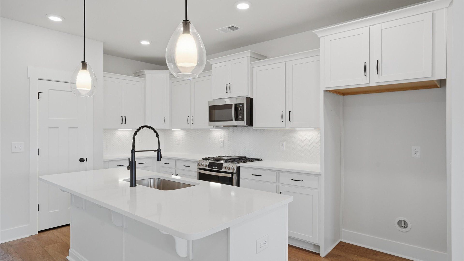 Exceptional kitchen featuring a spacious island, eye-catching pendant lights, and modern finishes at Harrier Point
