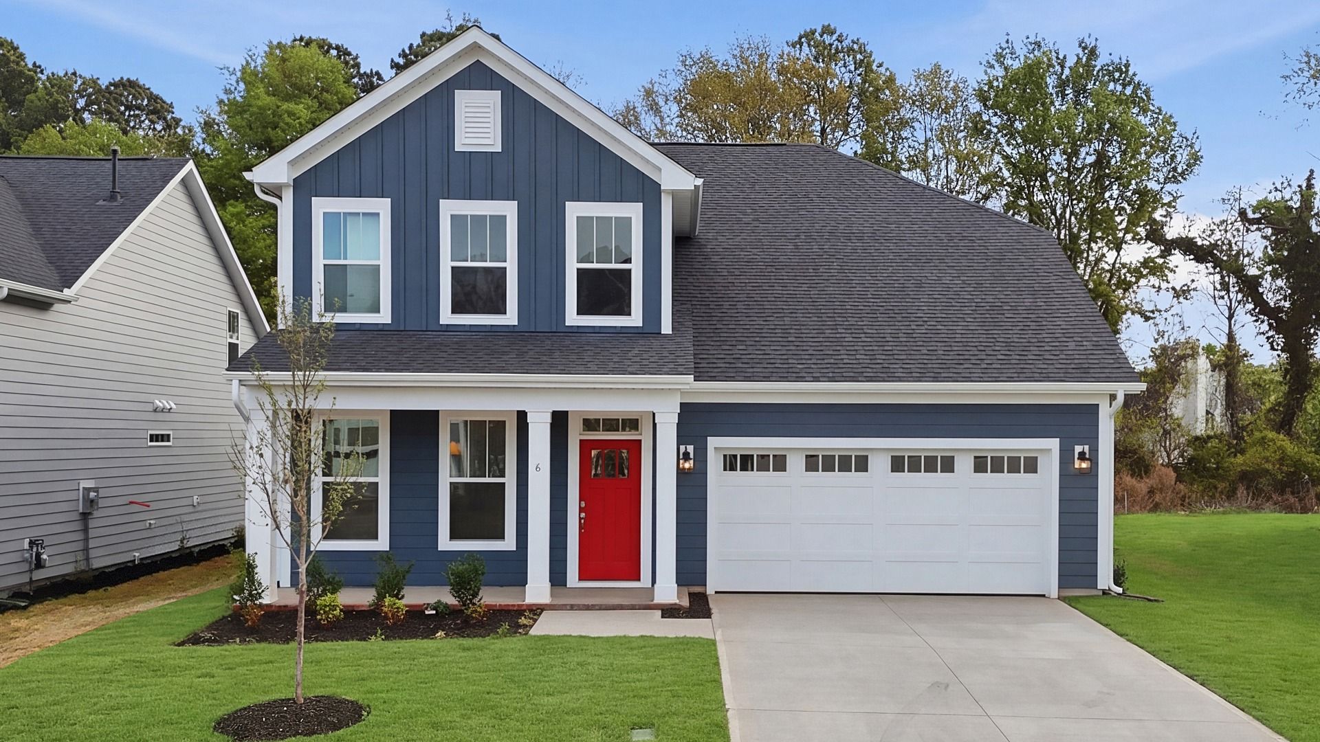 Two story home in Greenville, SC with blue exterior, two car garage, and columns at Pelham Crossing by DRB Homes