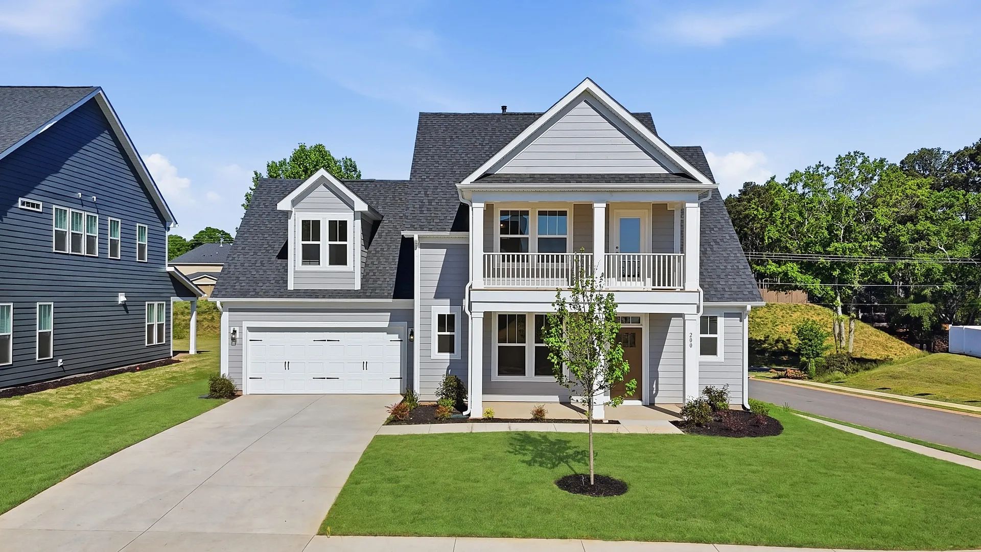 White exterior Sutherland new two story home with stone columns, blue door & two car garage at Wells Crossing in Seneca, SC
