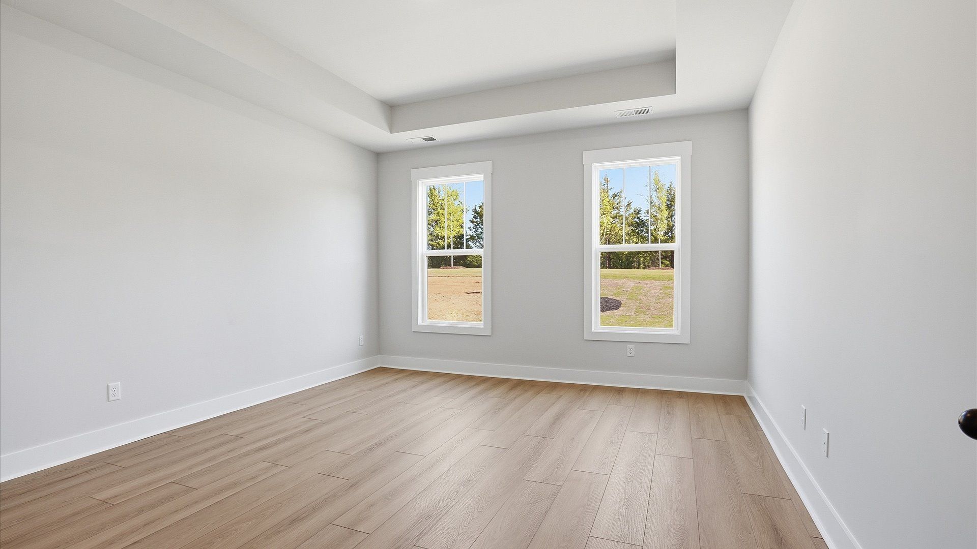 Serene and stylish primary bedroom featuring hardwood flooring and a thoughtful, modern layout at Benjamin's Grove