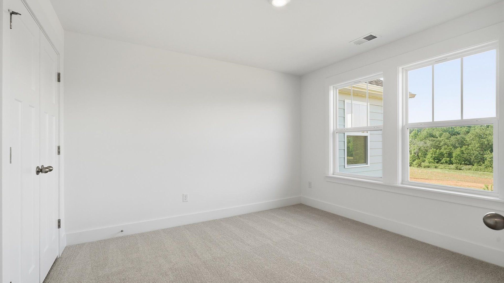 Refined bedroom design with large windows for daylight-filled mornings and peaceful views at the Pinebrook community