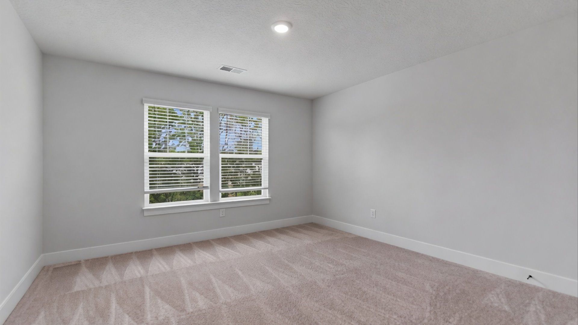 Highly functional bedroom with large windows, carpeted flooring, and tasteful finishes throughout at Village at Midway