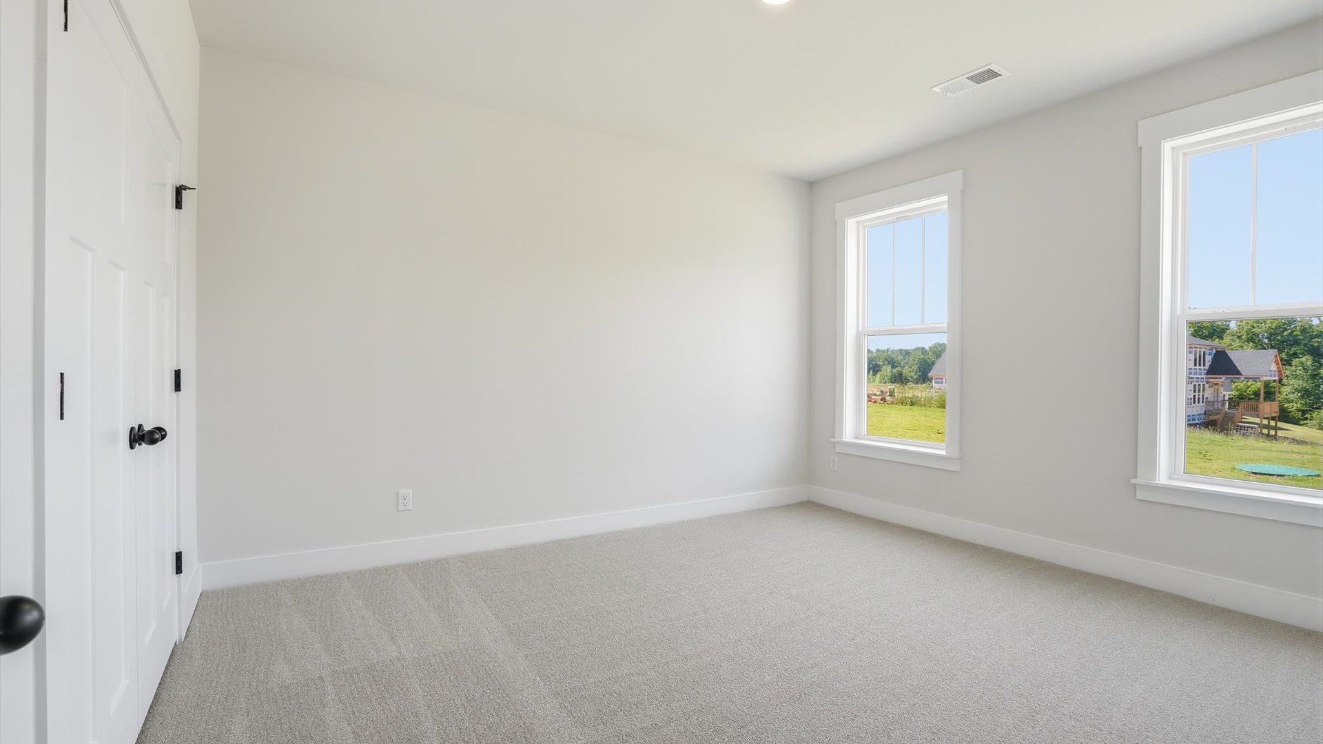Elegant bedroom retreat featuring soft carpet and oversized windows that create a bright, welcoming space