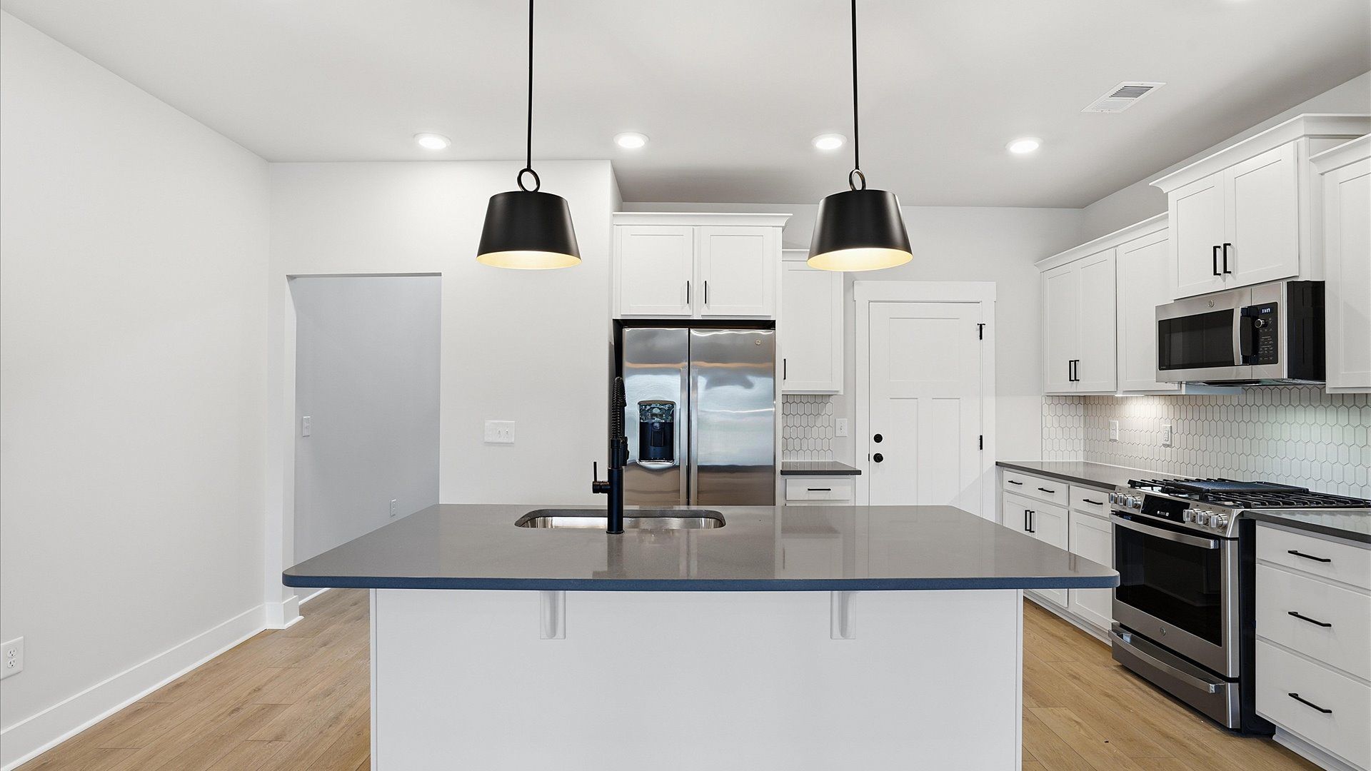 Vibrant and open kitchen centered around a an island with elegant pendant lighting above located at Silo Ridge