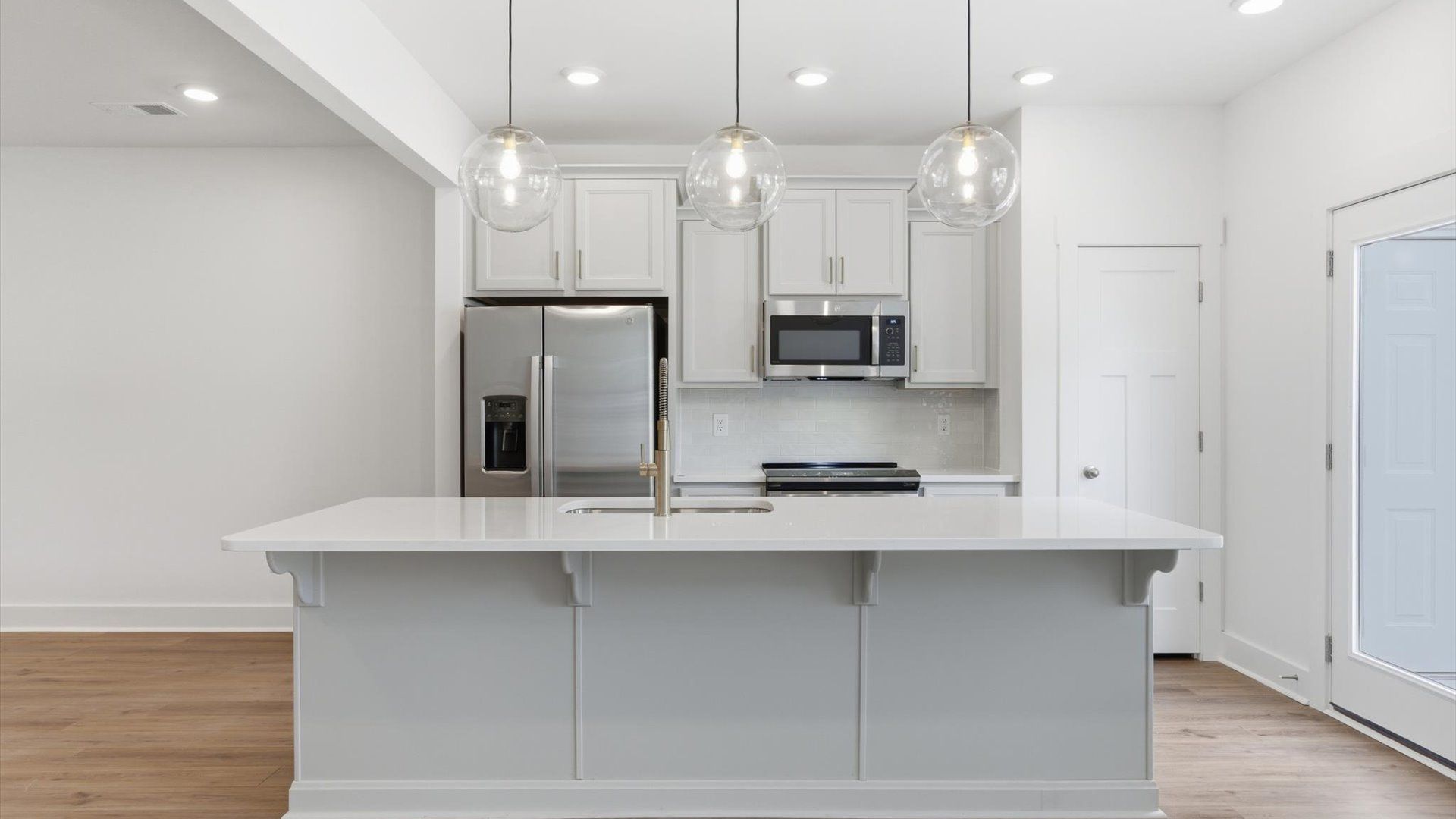 Exceptional kitchen featuring a spacious island, eye-catching pendant lights, and modern finishes at Gresham Station