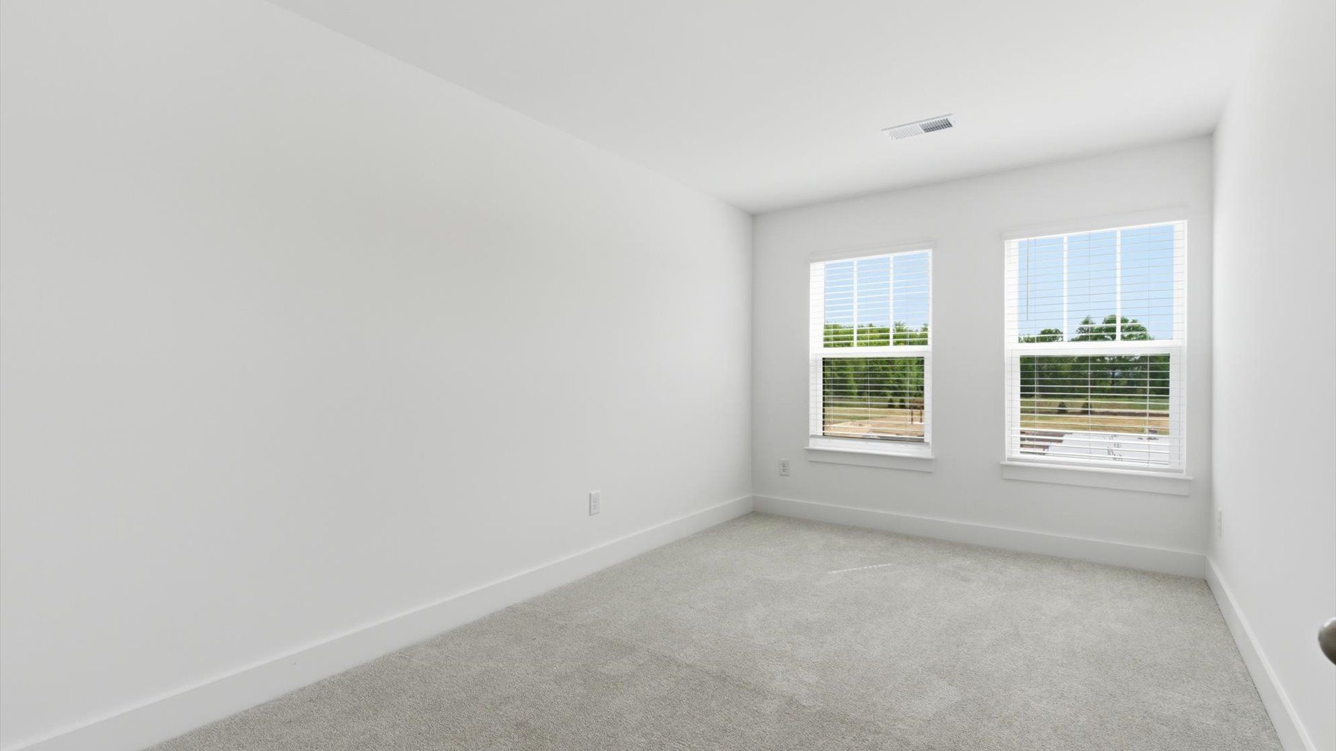 Notable bedroom offering soft carpet, a walk-in closet, and expansive windows overlooking the yard