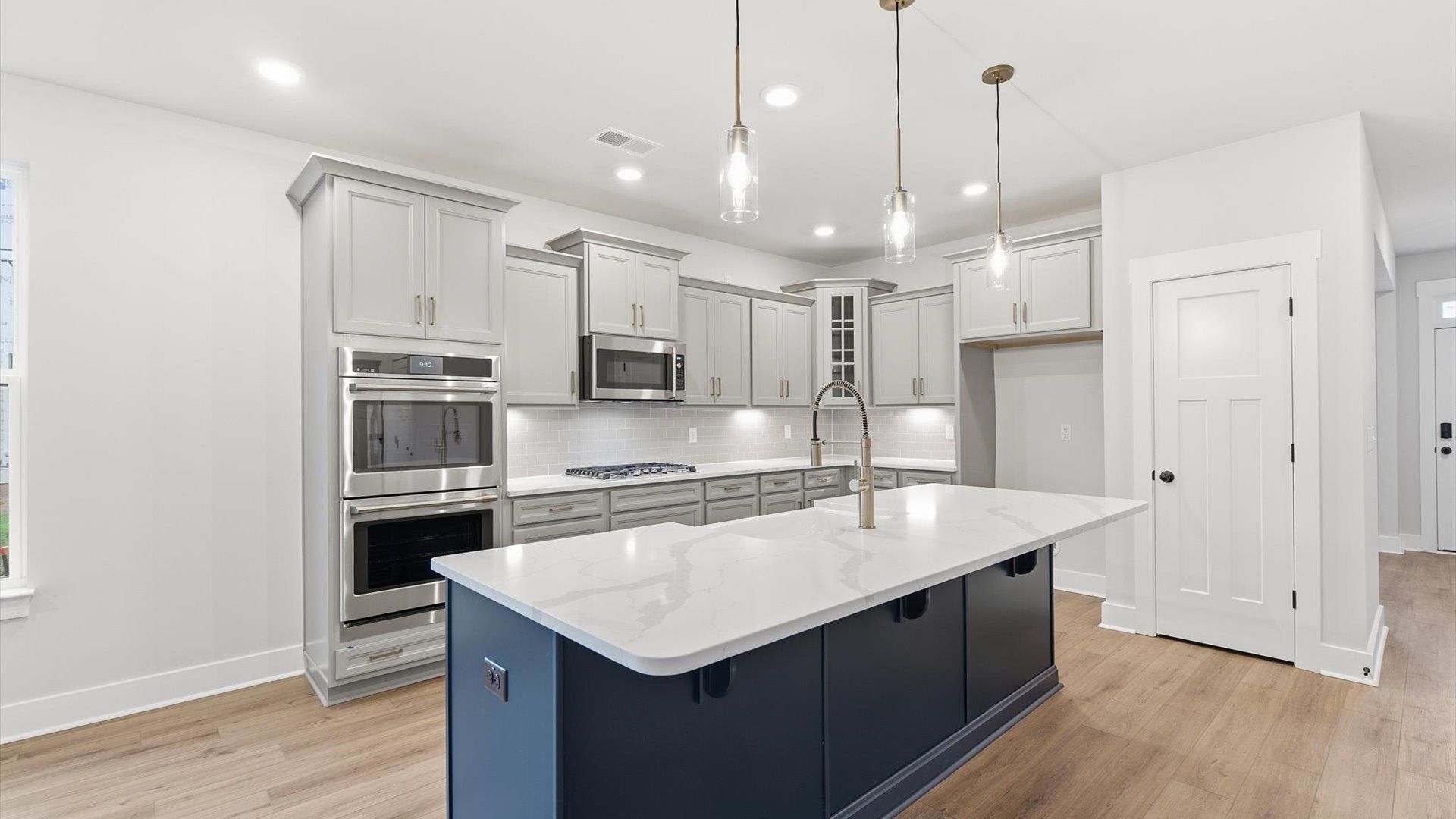Accomplished kitchen design featuring pendant lighting above a statement island for both prep and gathering at Woodglen