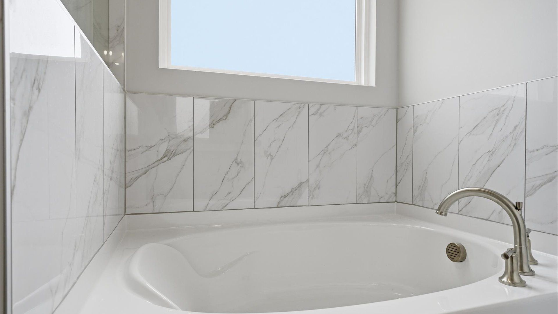 Superior en-suite primary bathroom with natural light and a large soaking tub—crafted with high standards in mind