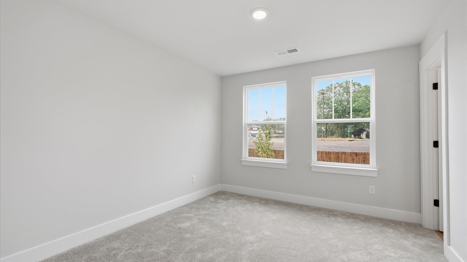 Highly functional bedroom with large windows, carpeted flooring, and tasteful finishes throughout at Woodglen